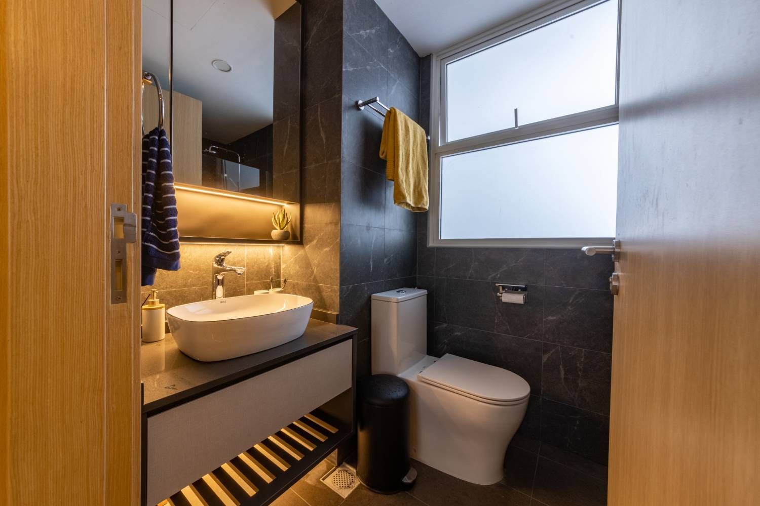 Contemporary Black Tiled Bathroom Design with White WC and Wall-Mounted Unit