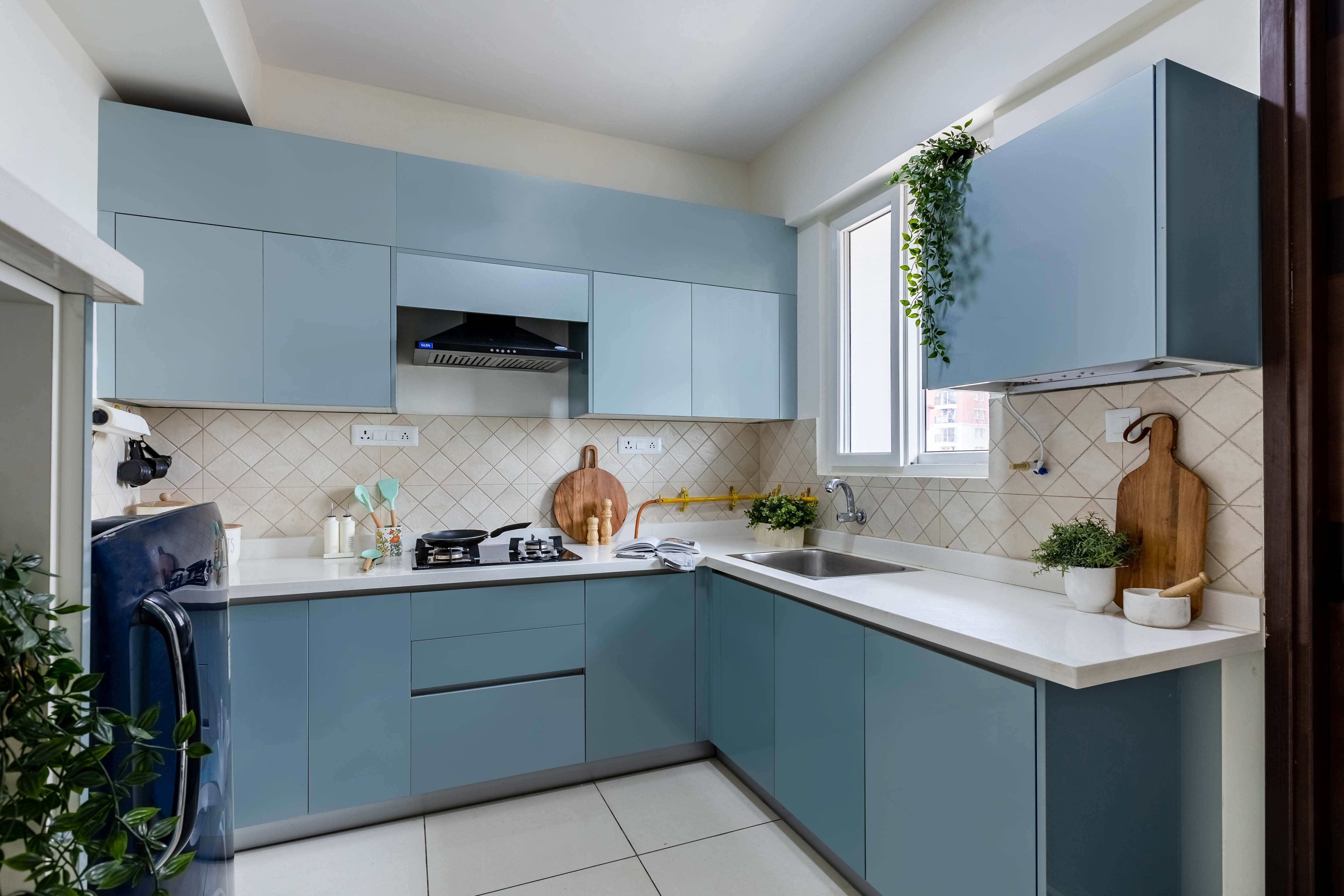 Modern L-Shaped Kitchen Design With Blue Cabinets And Diamond-Patterned Dado Tiles