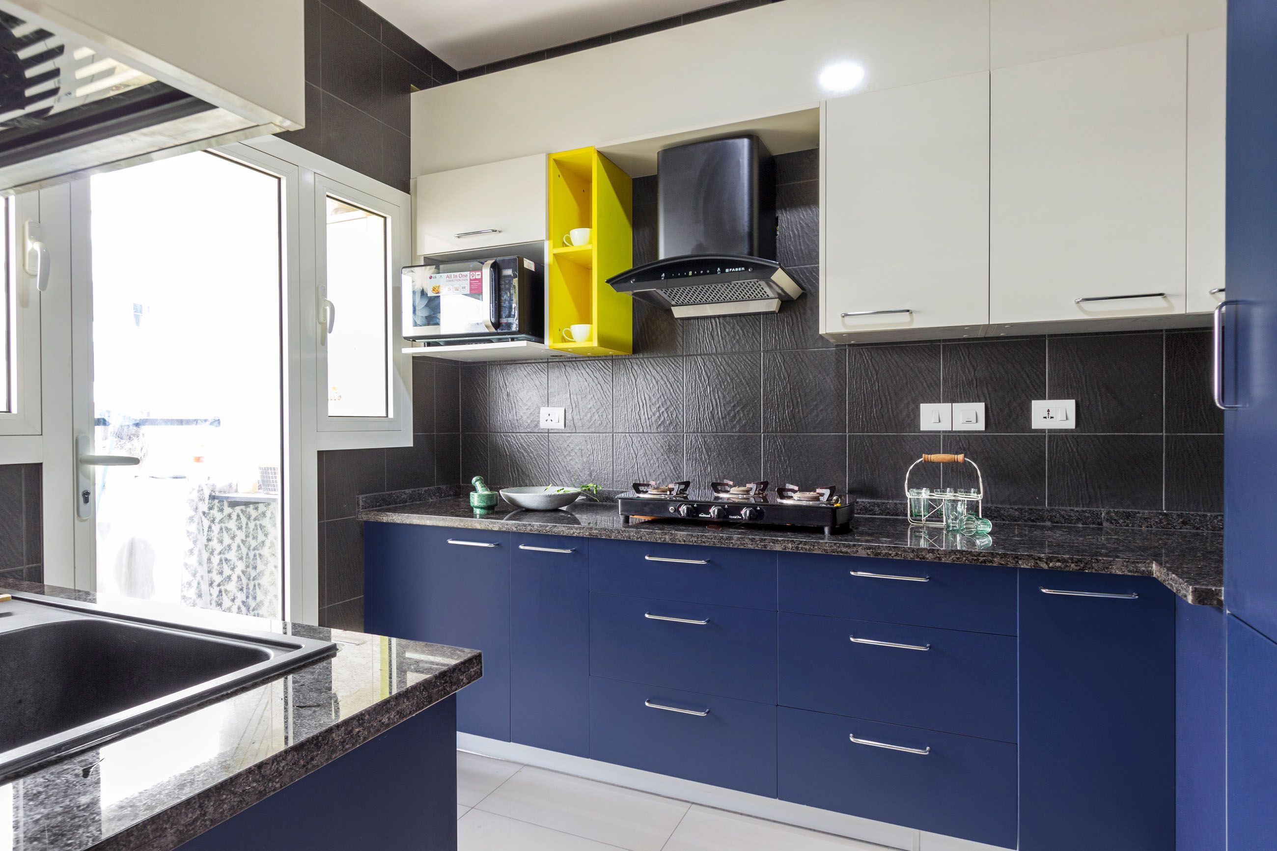 Contemporary Modular Blue And Champagne-Toned L Shaped Kitchen Cabinet Design With Dark Grey Textured Backsplash
