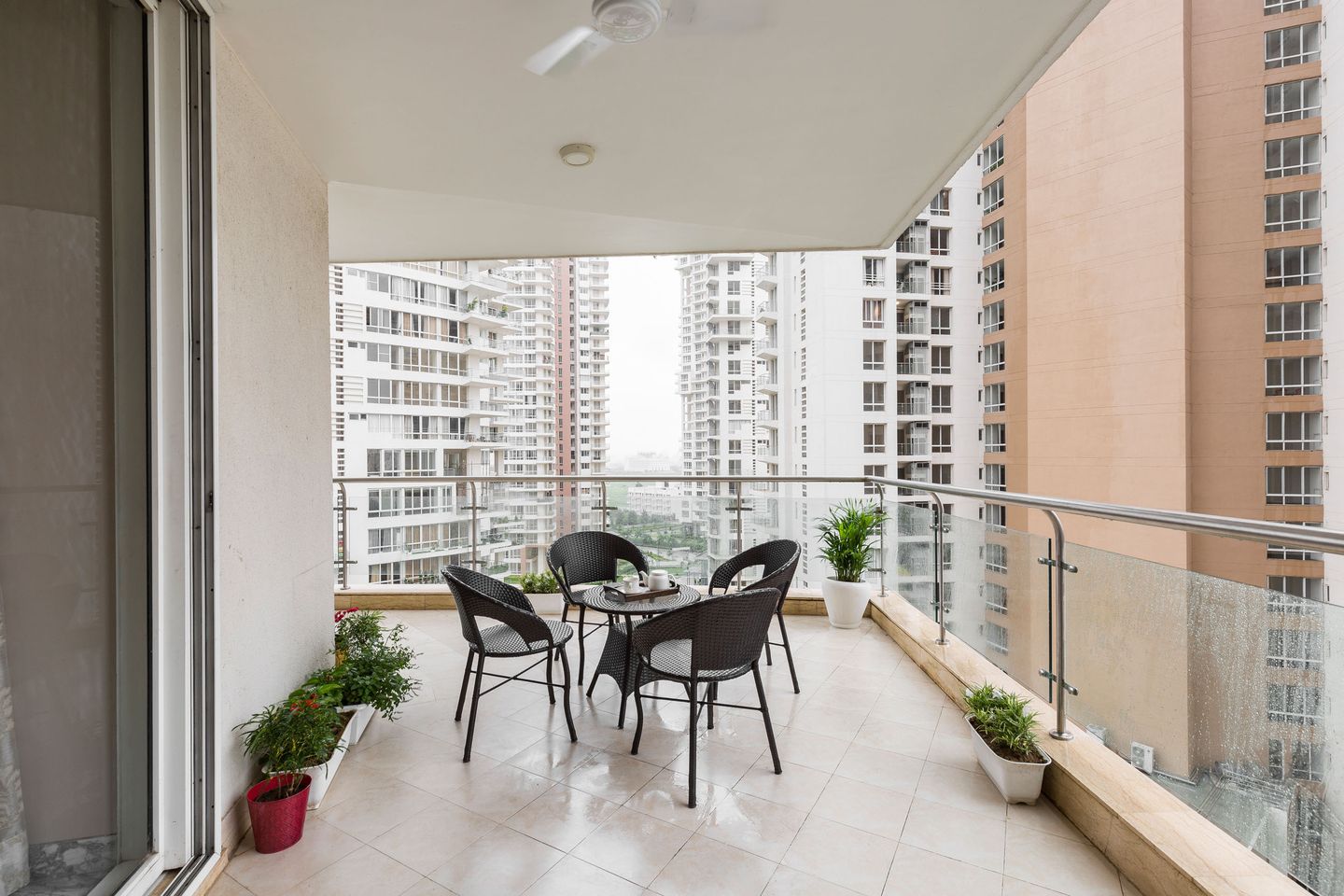 Minimal Balcony Design with Off-White Wall, Ceramic Flooring, and Dark Brown Rattan Furniture - Livspace