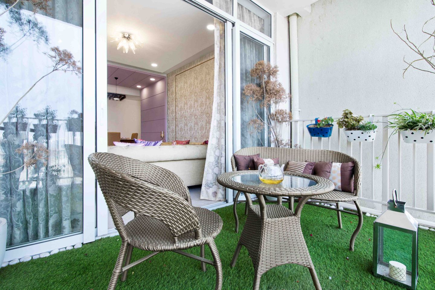 Modern Balcony Design with White Wall Paint, Grass Mat, Cane Seaters, and Round Coffee Table - Livspace