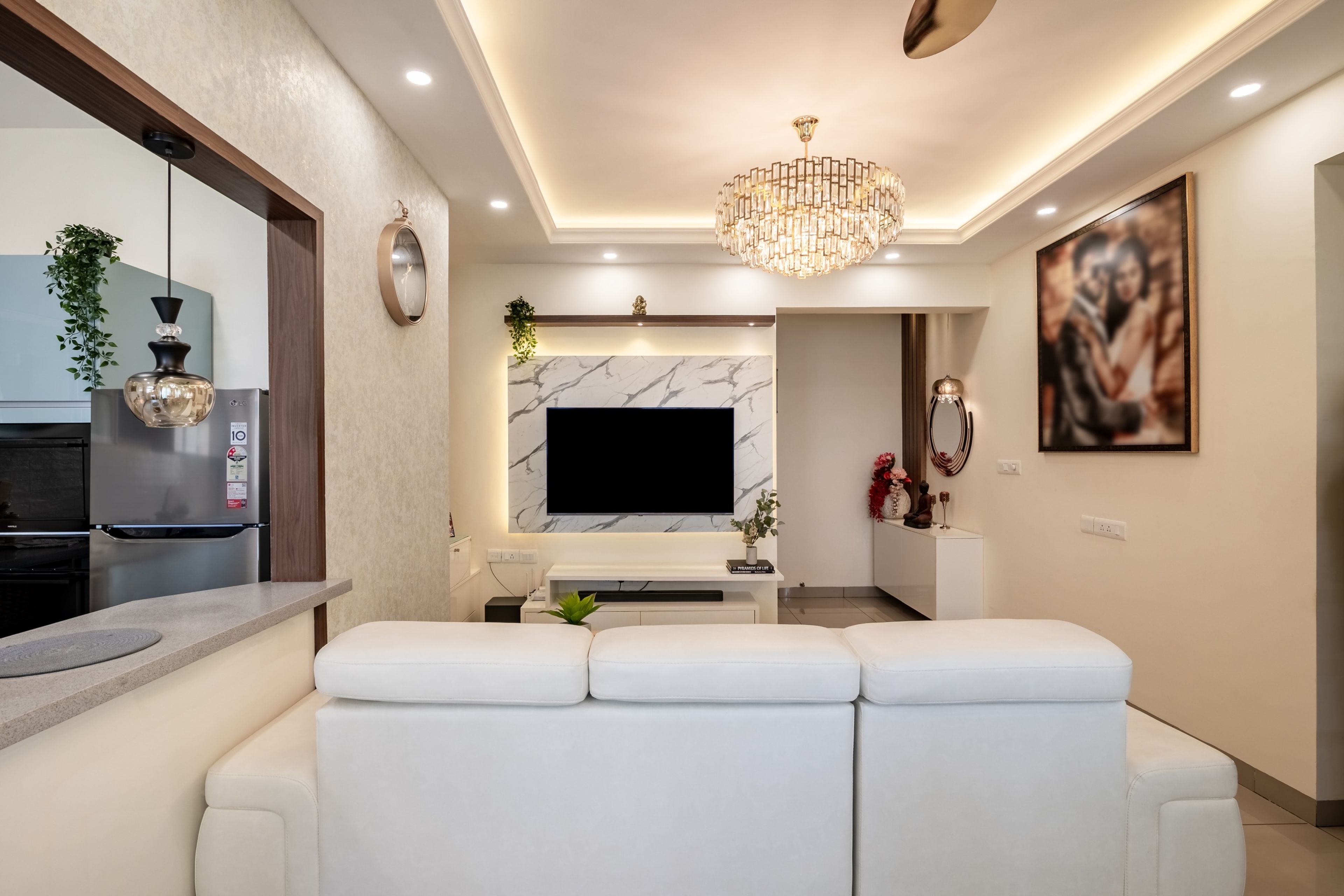 Contemporary false ceiling with chandelier and strip lighting in a room - Livspace