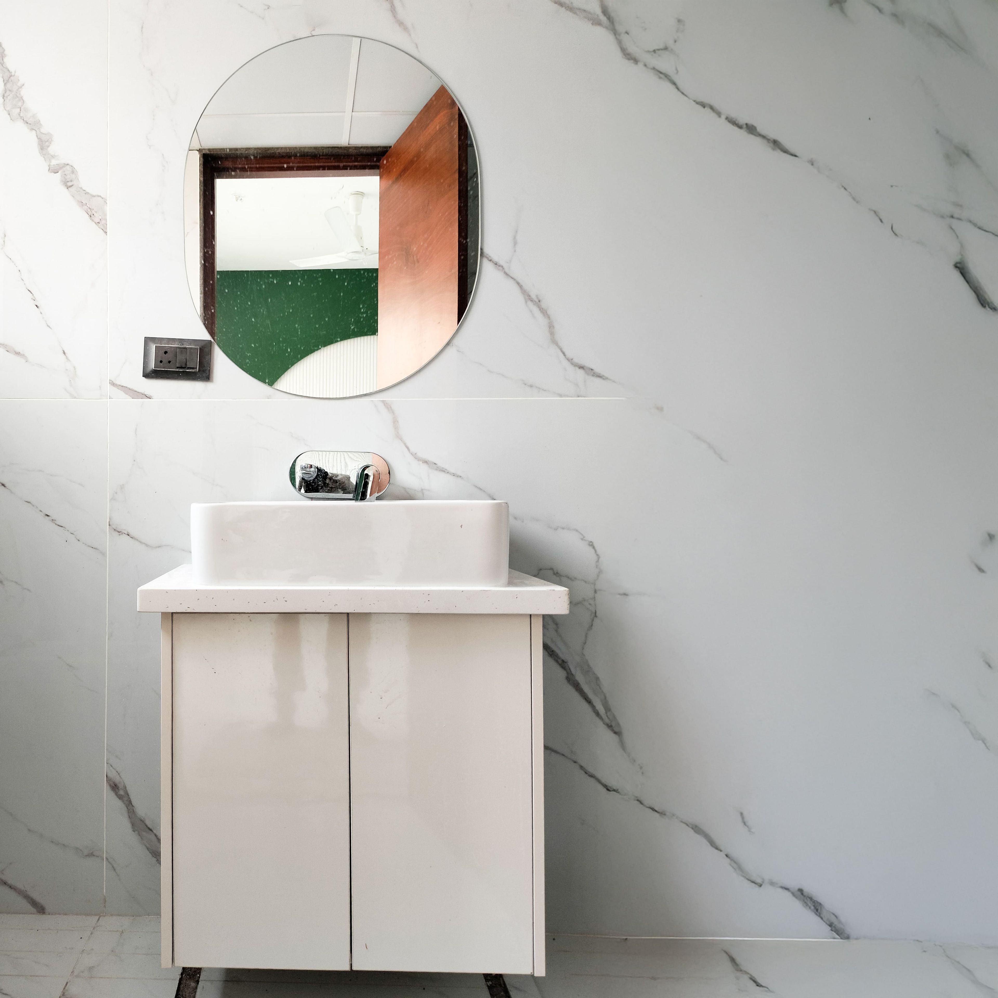 Btahroom Design with Cream Cabinets and Round Mirror