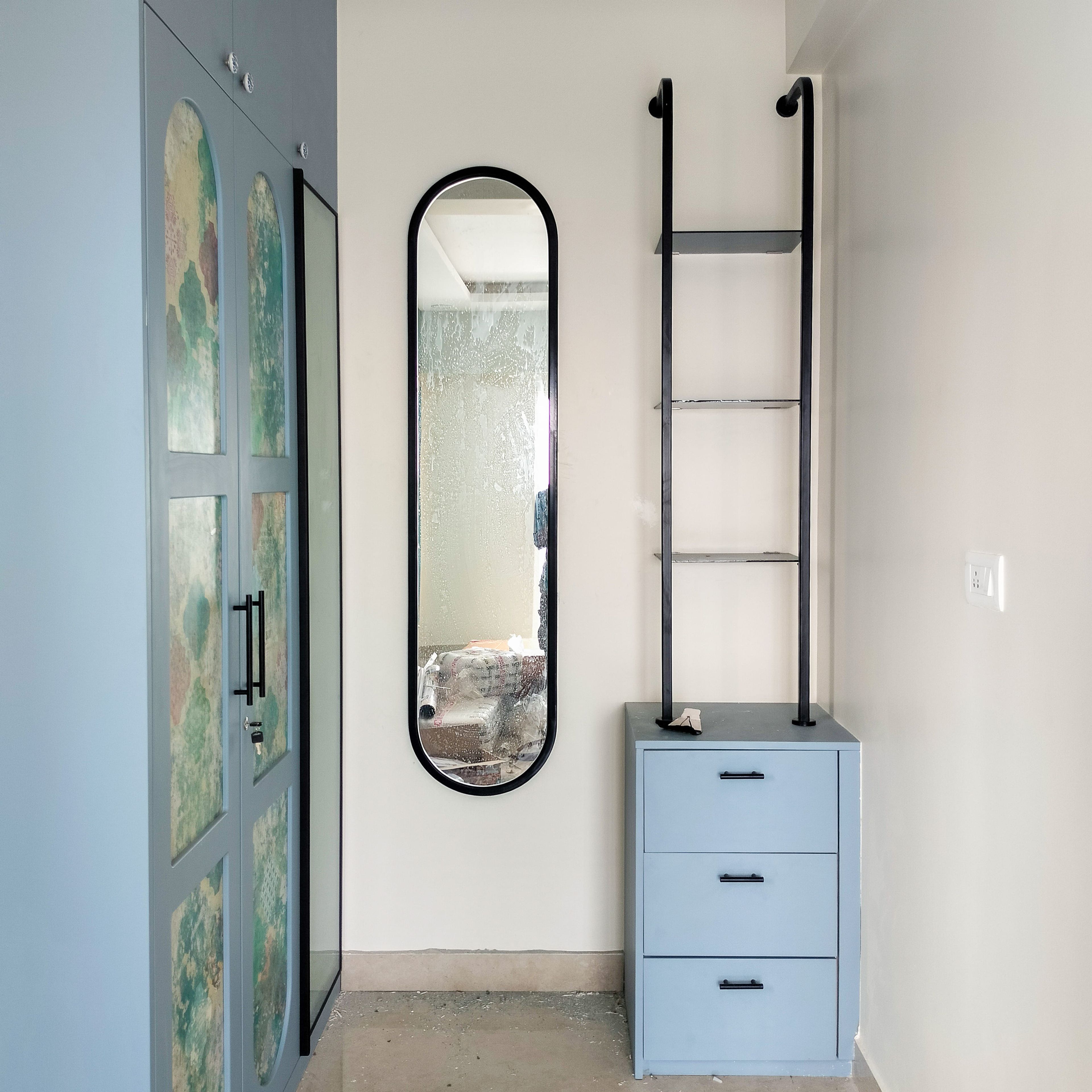 Oval Mirror on a White Wall with Blue Wall Mounted Cabinets