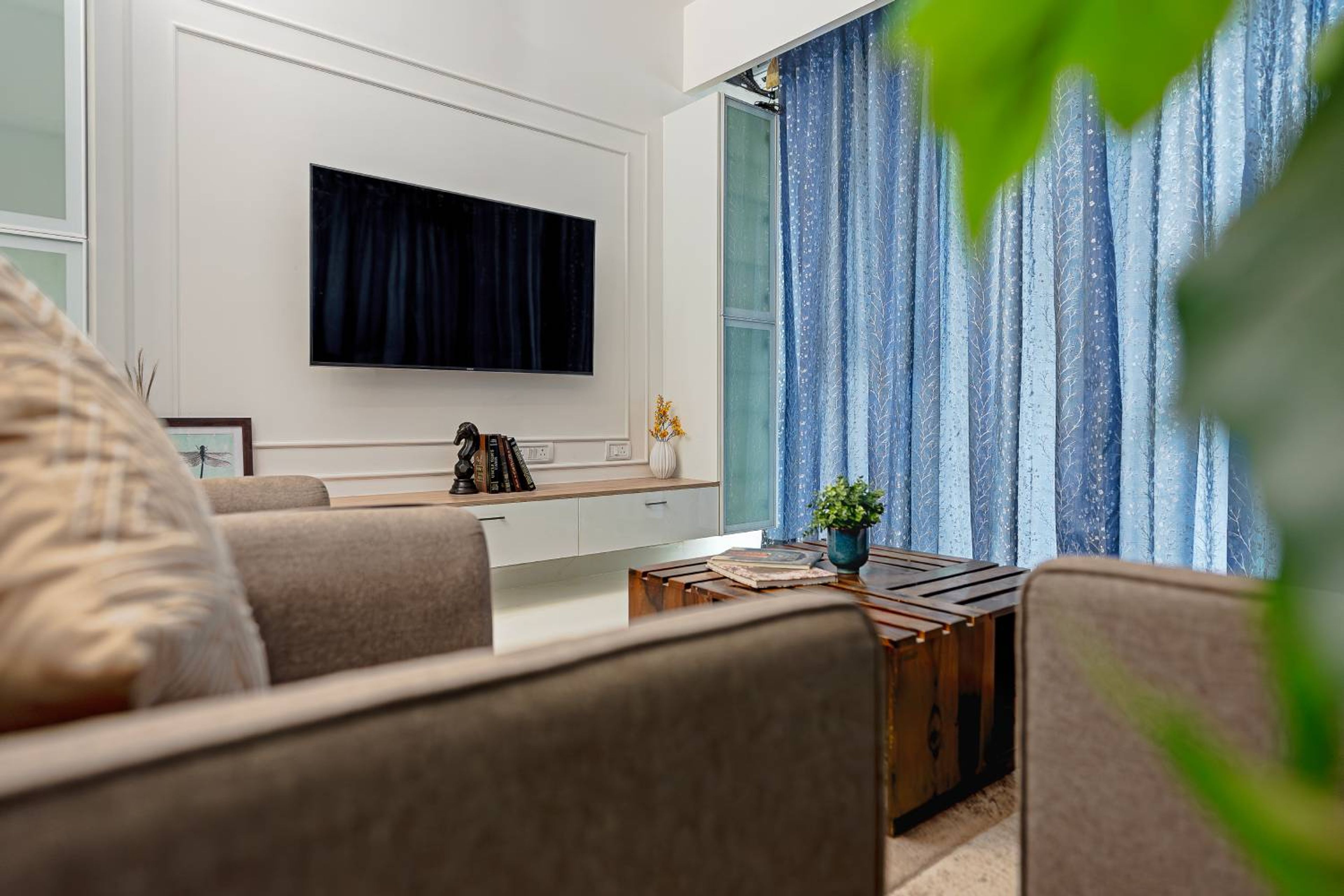 Living Room Design with Wooden Table and Wall Mounted TV Unit with White Backsplash Wall