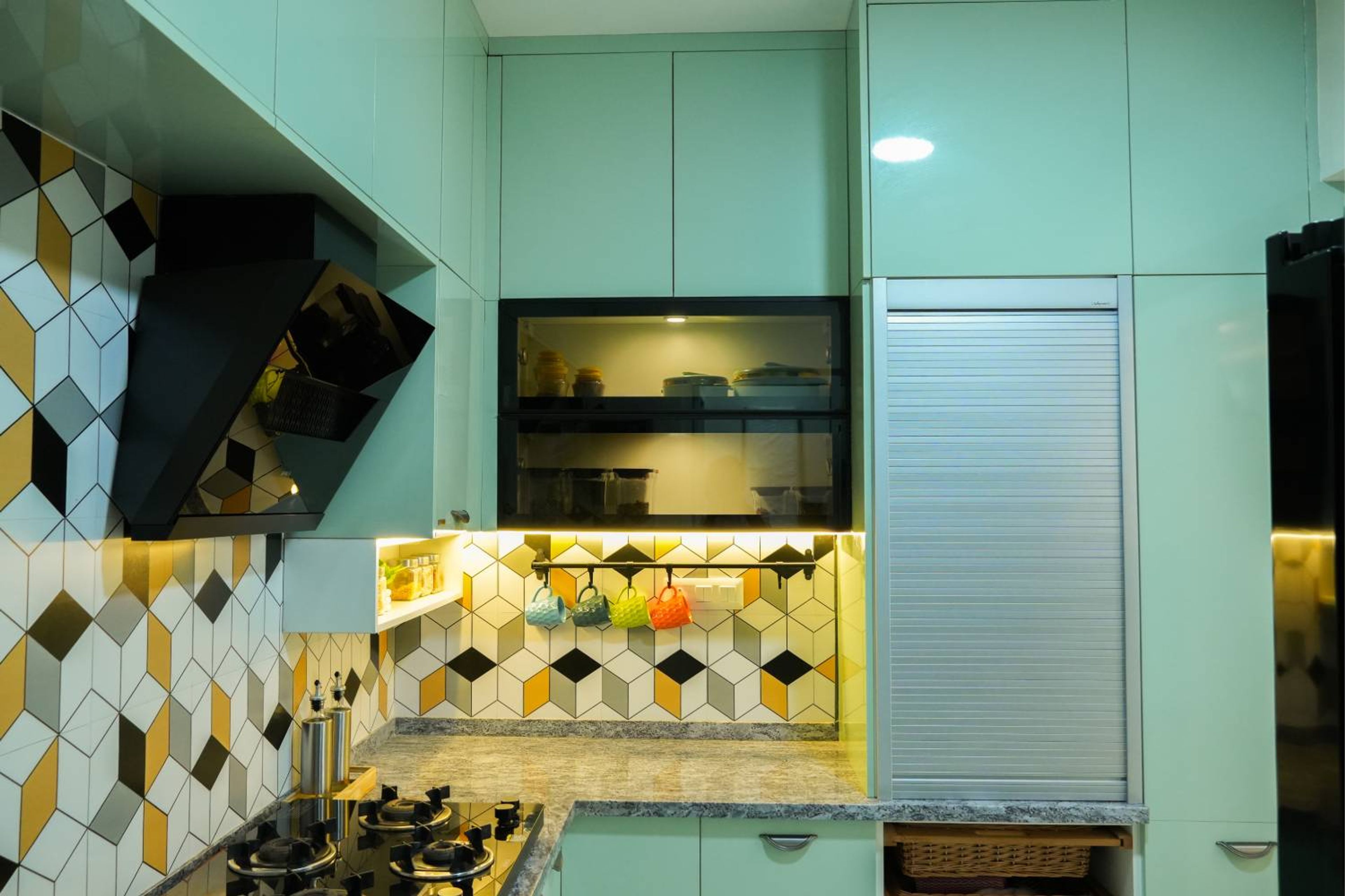 L-Shaped Kitchen Design with Mint Green Cabinets and Patterned Geometric Backsplash