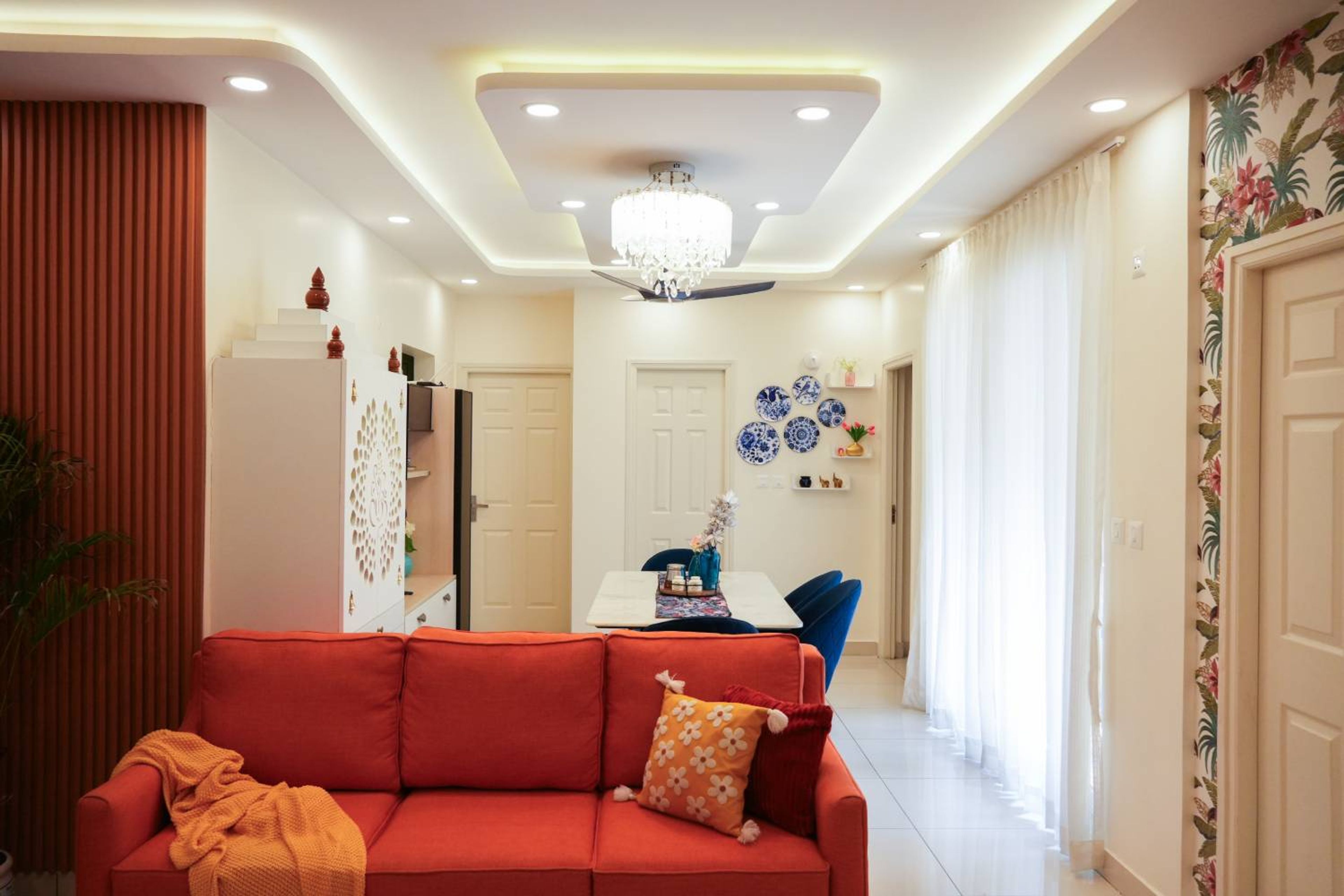 Living Room Design with Orange Sofa and False Ceiling with Cove Lights and Chandelier