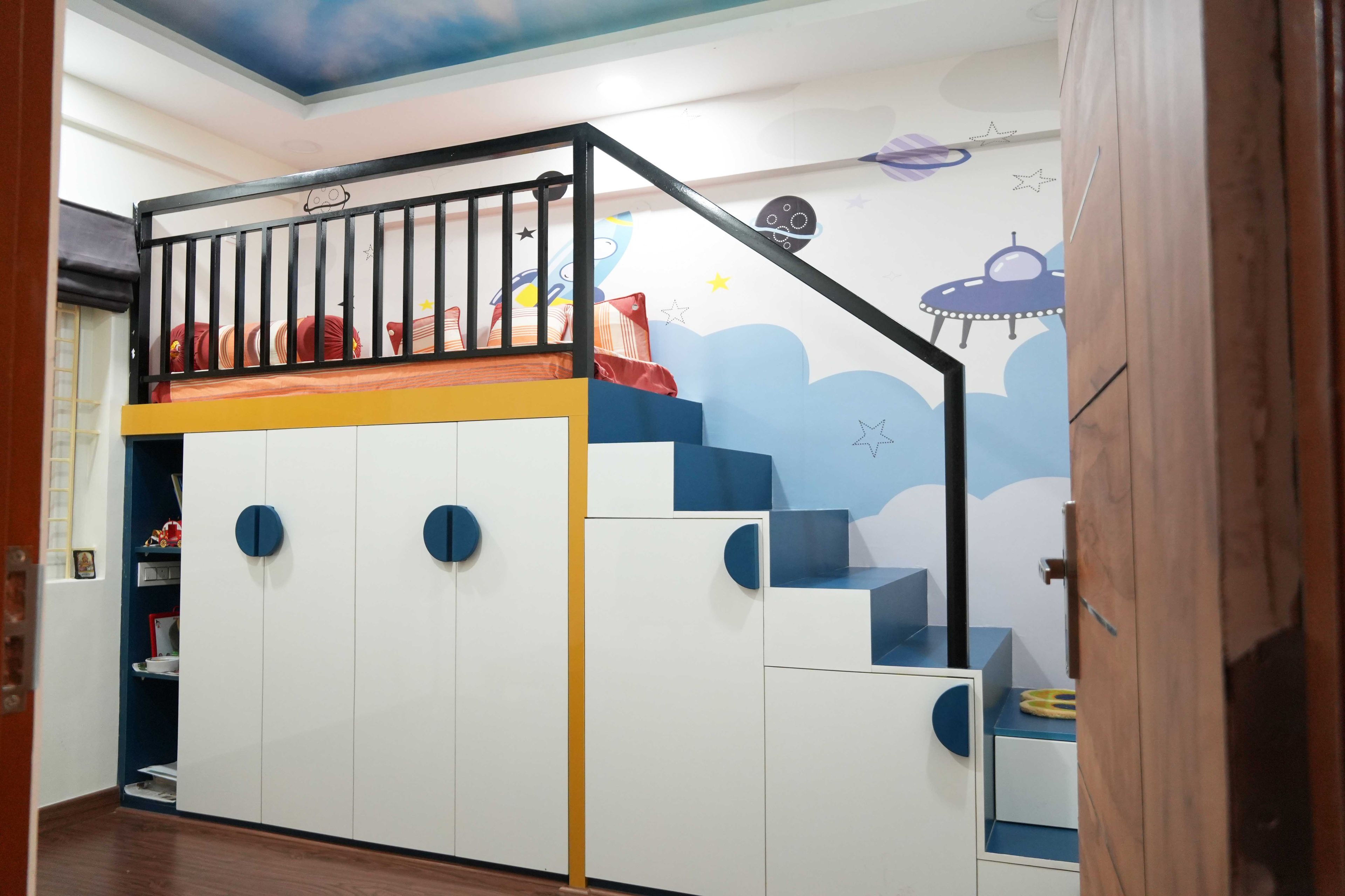 Kids Bedroom Design with Loft Bed with Integrated Storage and Wardrobe Units Underneath and Space-Themed Wall