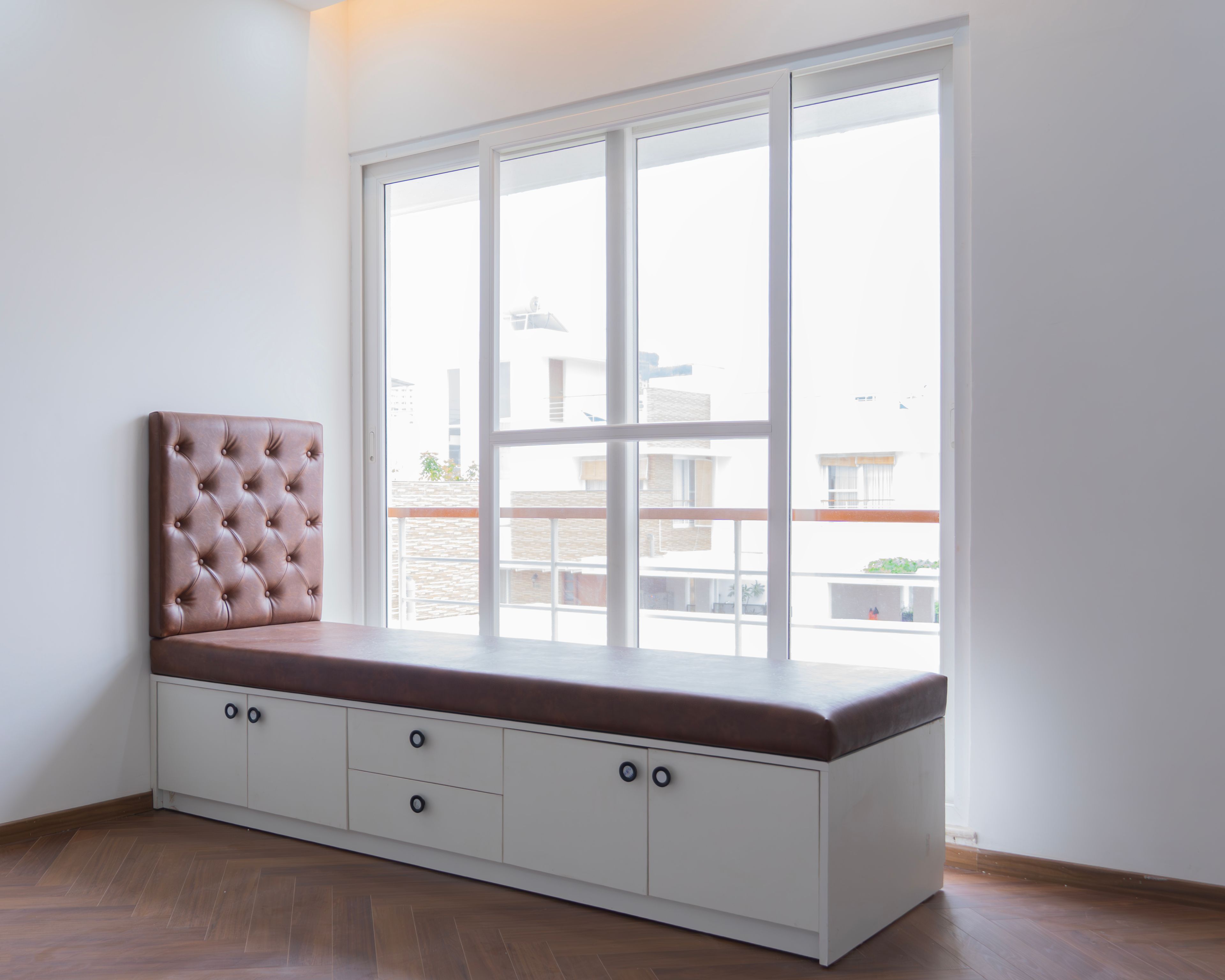 Window Design with Brown Upholstered Seating and White Sliding Panels
