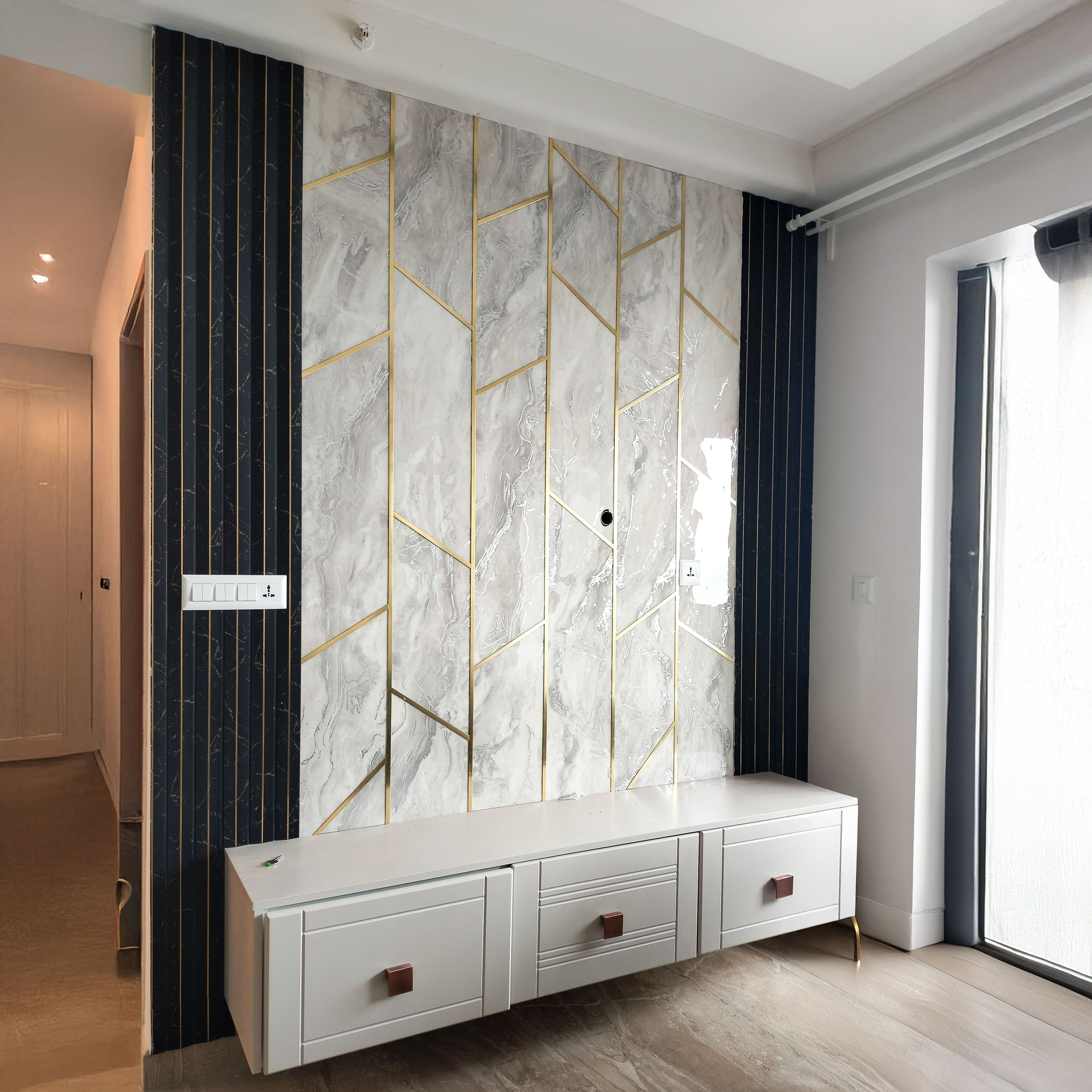 TV Unit Design with Marble-Textured Tiles with Gold Inlays and Vertical Black Panels