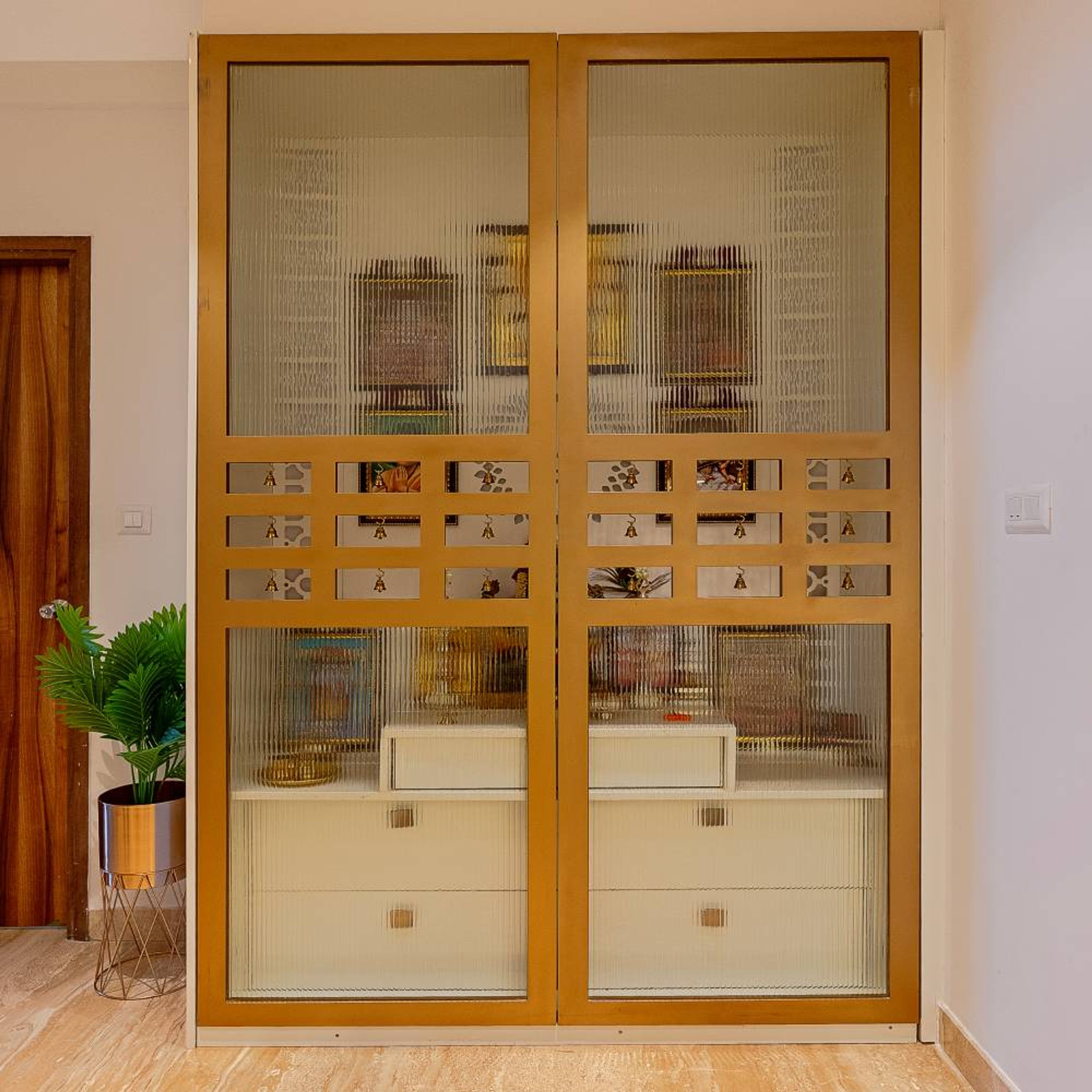 Modern Pooja Room Design with Golden Sliding Doors Fluted Glass and Laser-Cut Motifs