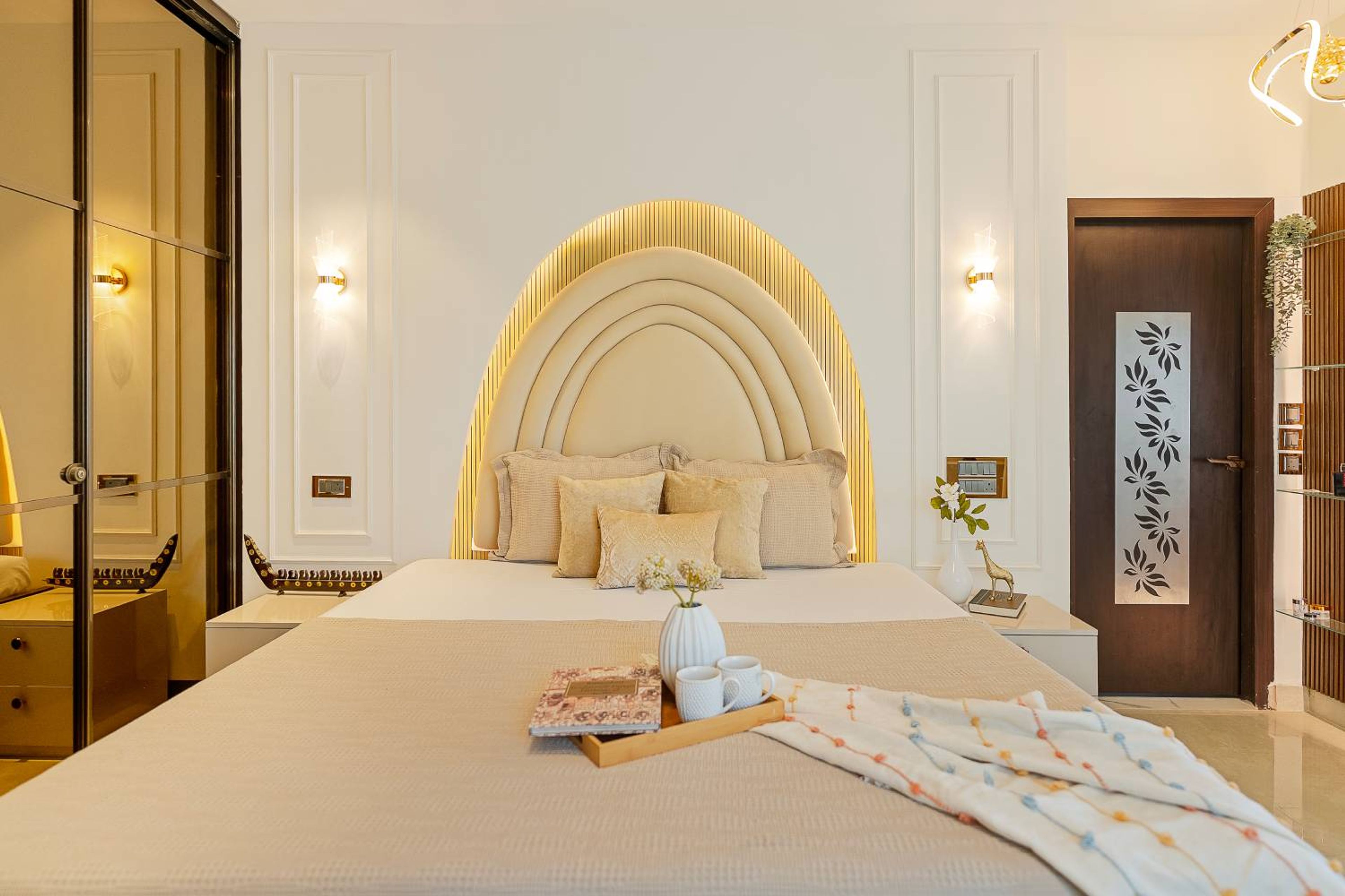 Bedroom Design with Cove Lit Arched Cushioned Headboard and White Wall with Trims
