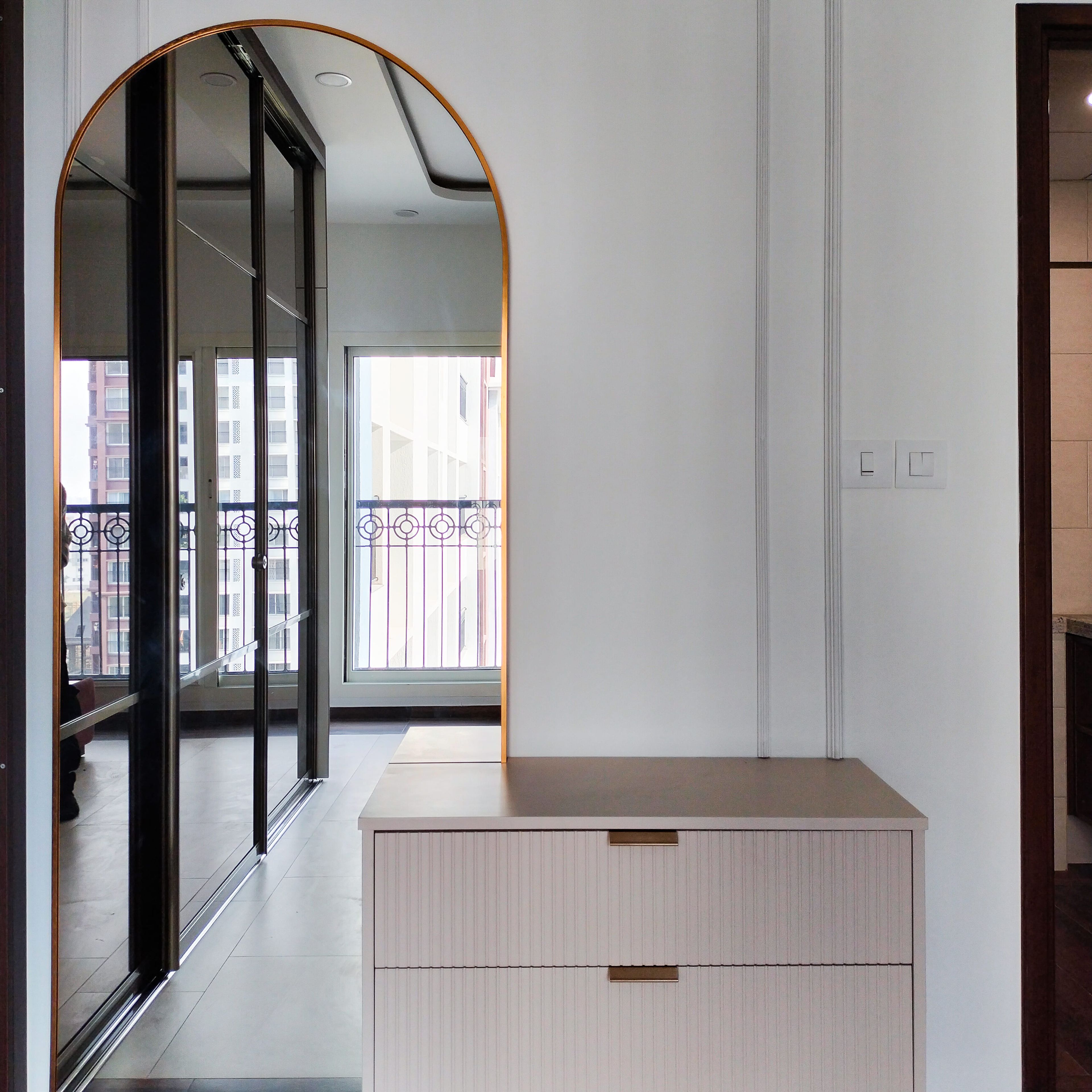 Arched mirror on a wall with storage unit