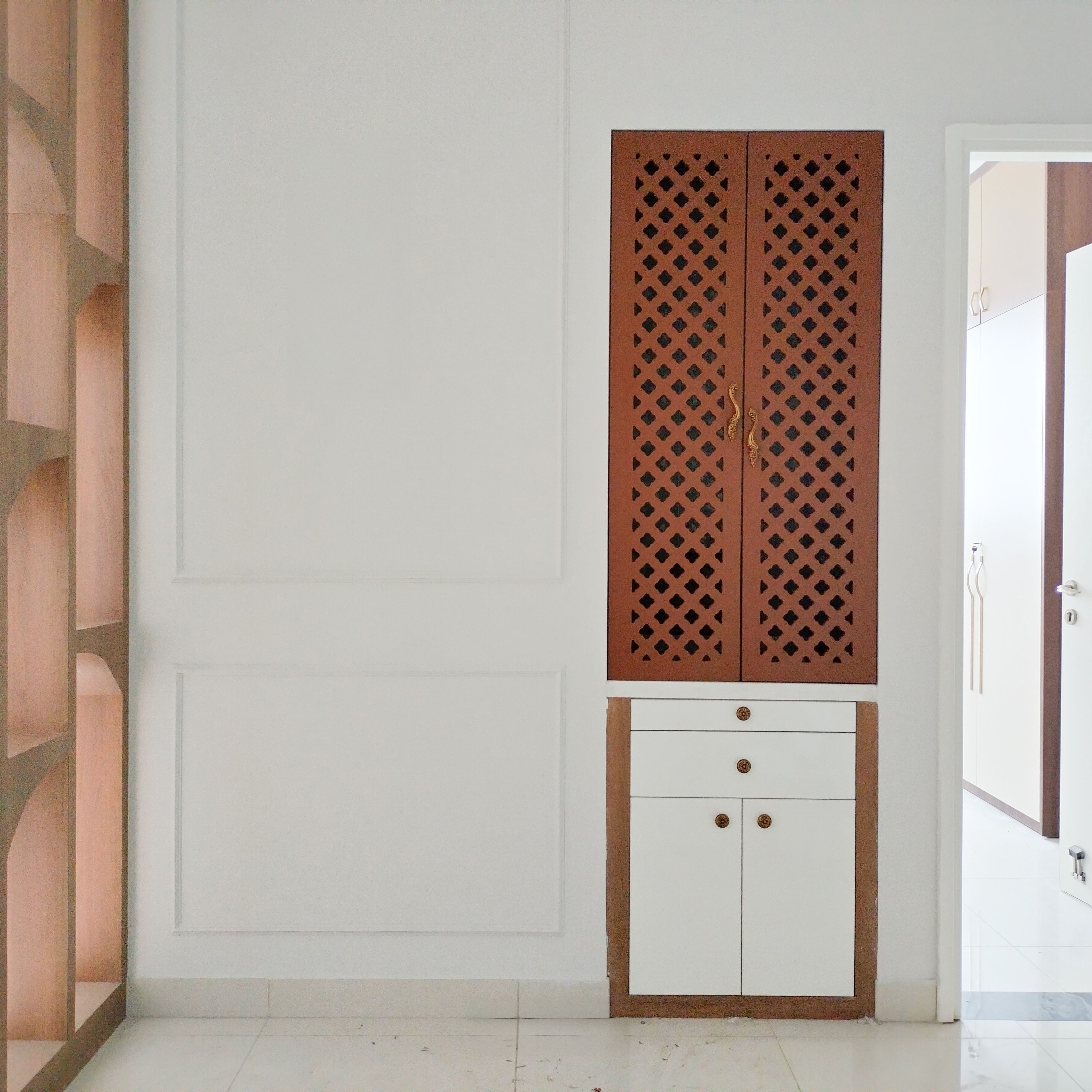 Pooja Room Design with Wooden Jali Patterned Door and White Drawers