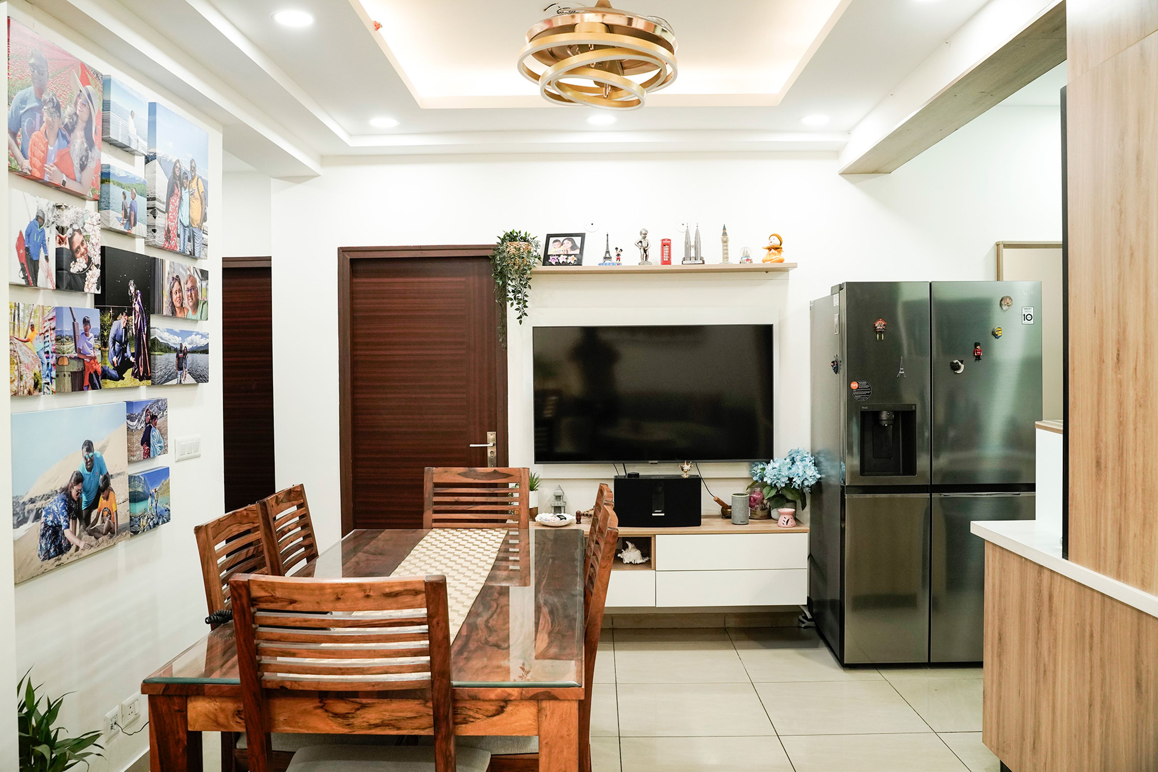 Living Cum Dining Room Design with 6-Seater Glass Dining Table and Wooden Chairs and TV Unit