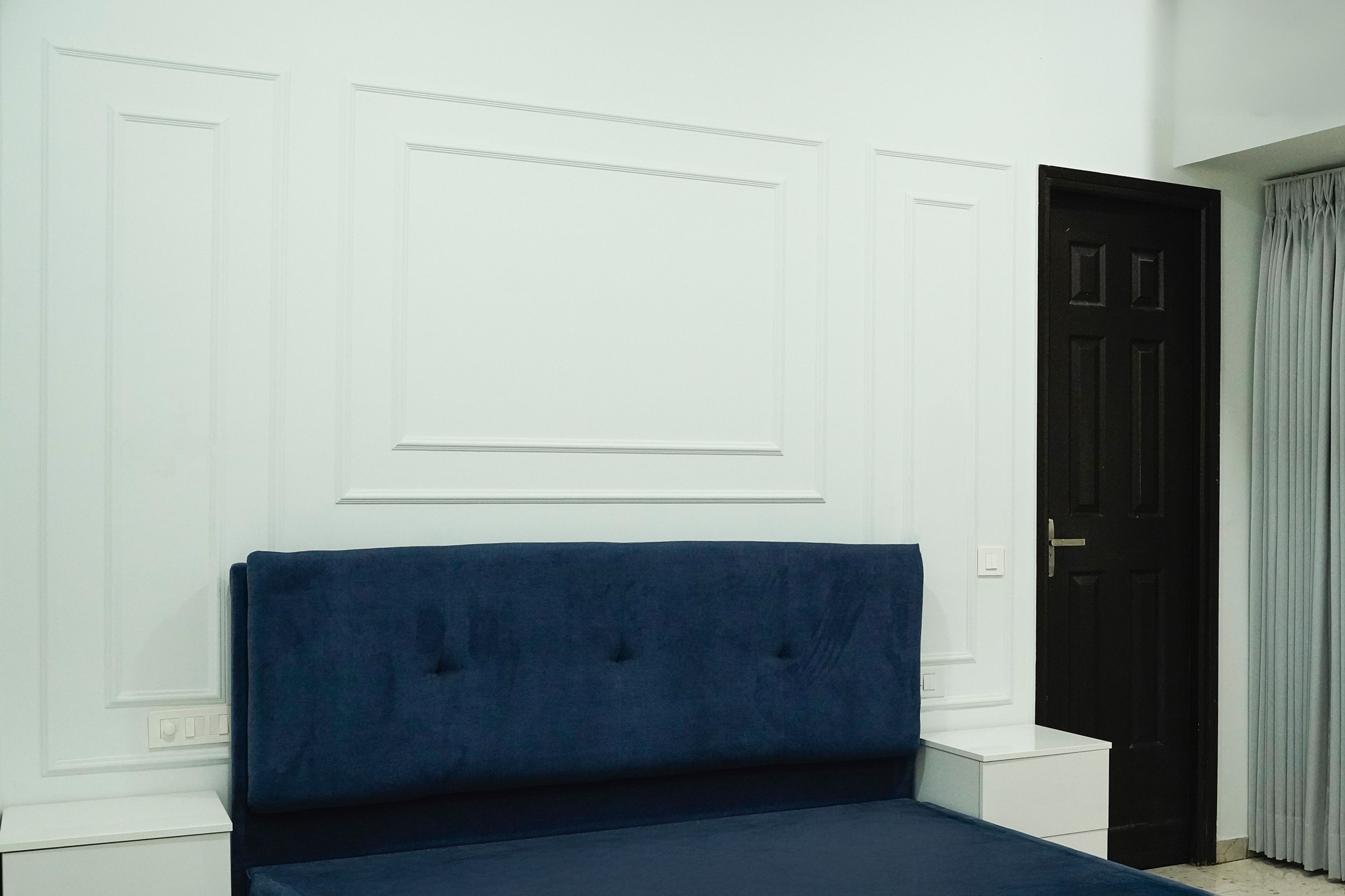 Room Design with Blue Velvelt Headboad Bed and White Wall with Trims