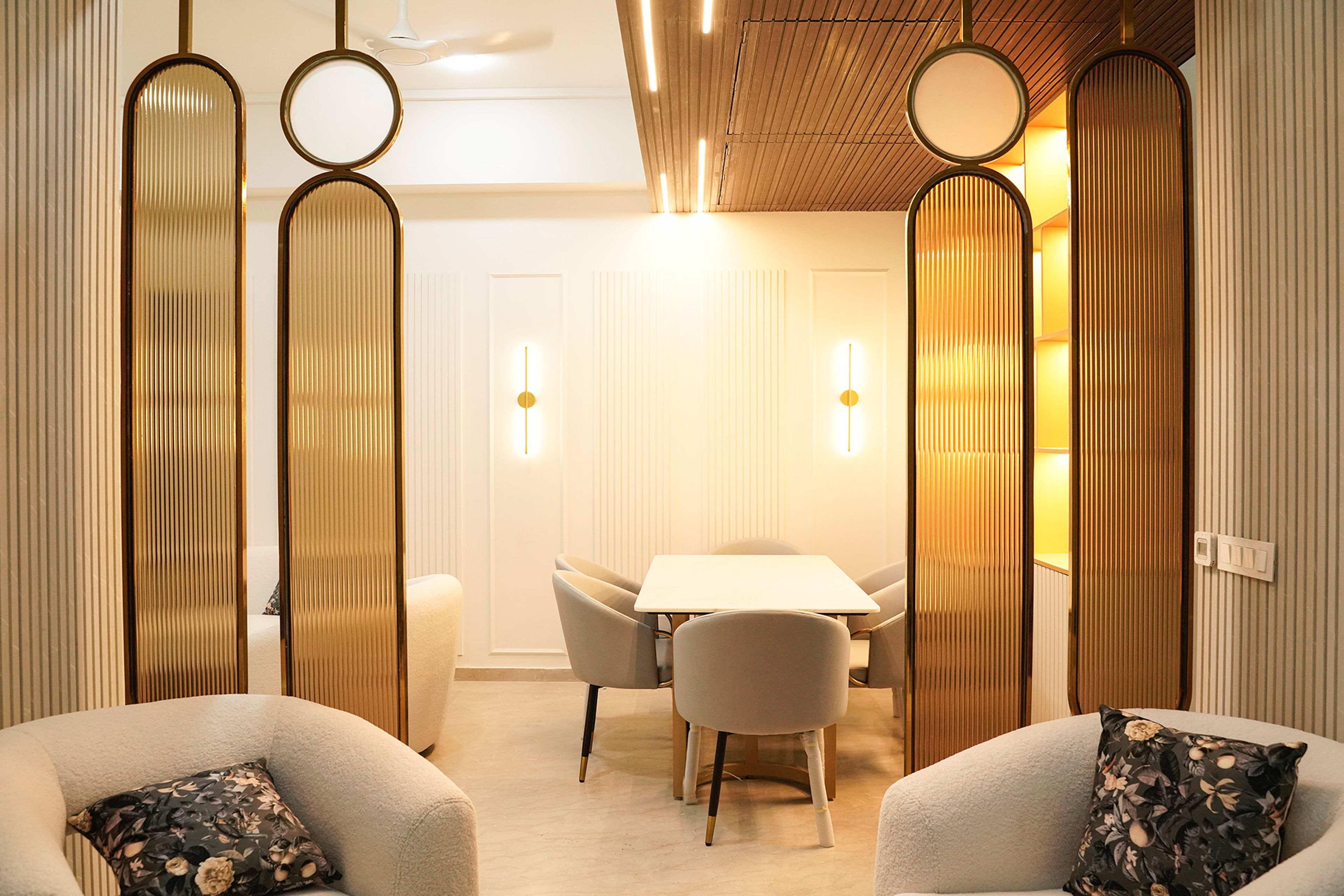 Living-Cum-Dining Room Design with Two Off-White Single Seater Sofas and Translucent Gold Room Dividers