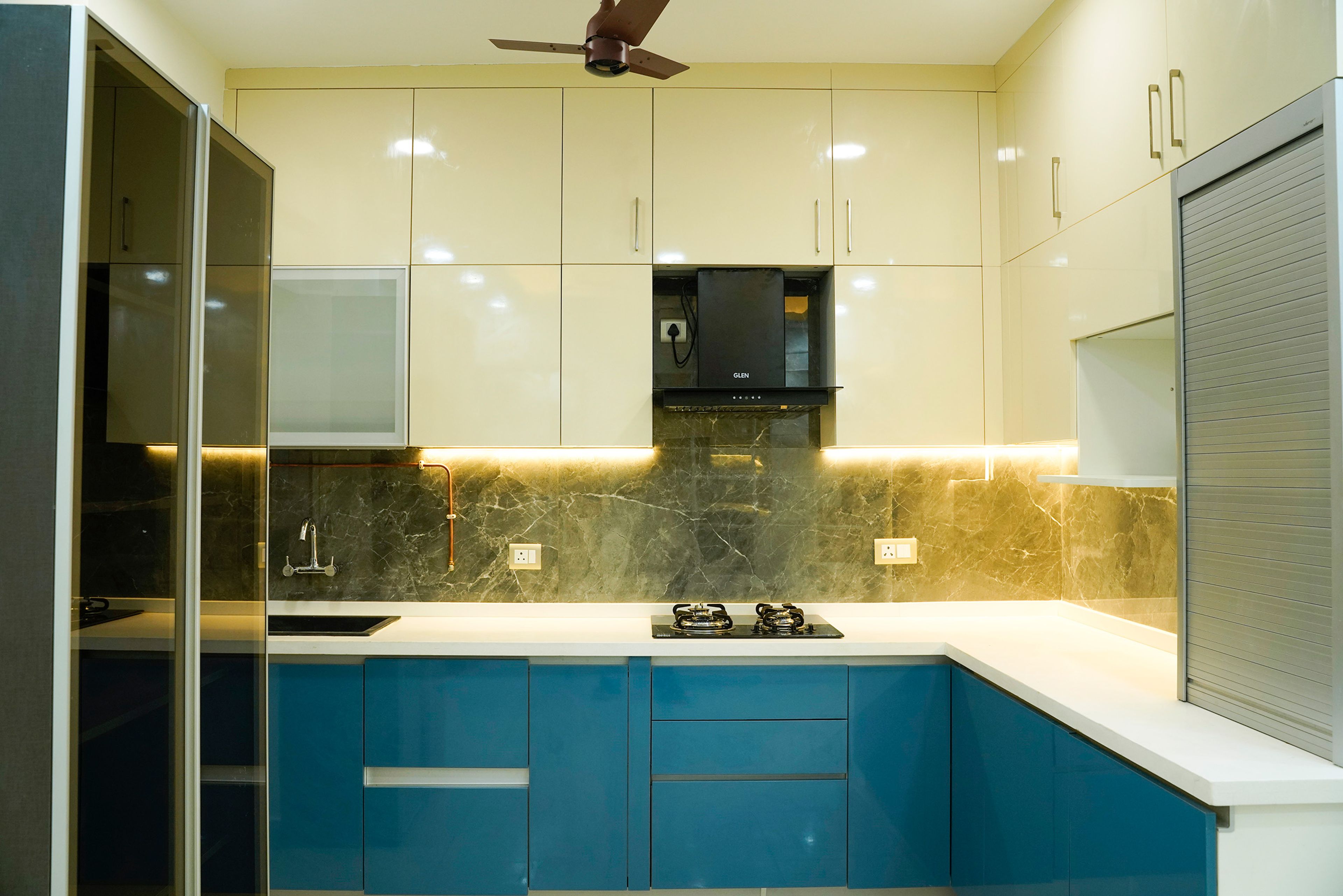 L-Shaped Kitchen Design with Blue and Cream Units and Black Marble Patterned Backsplash