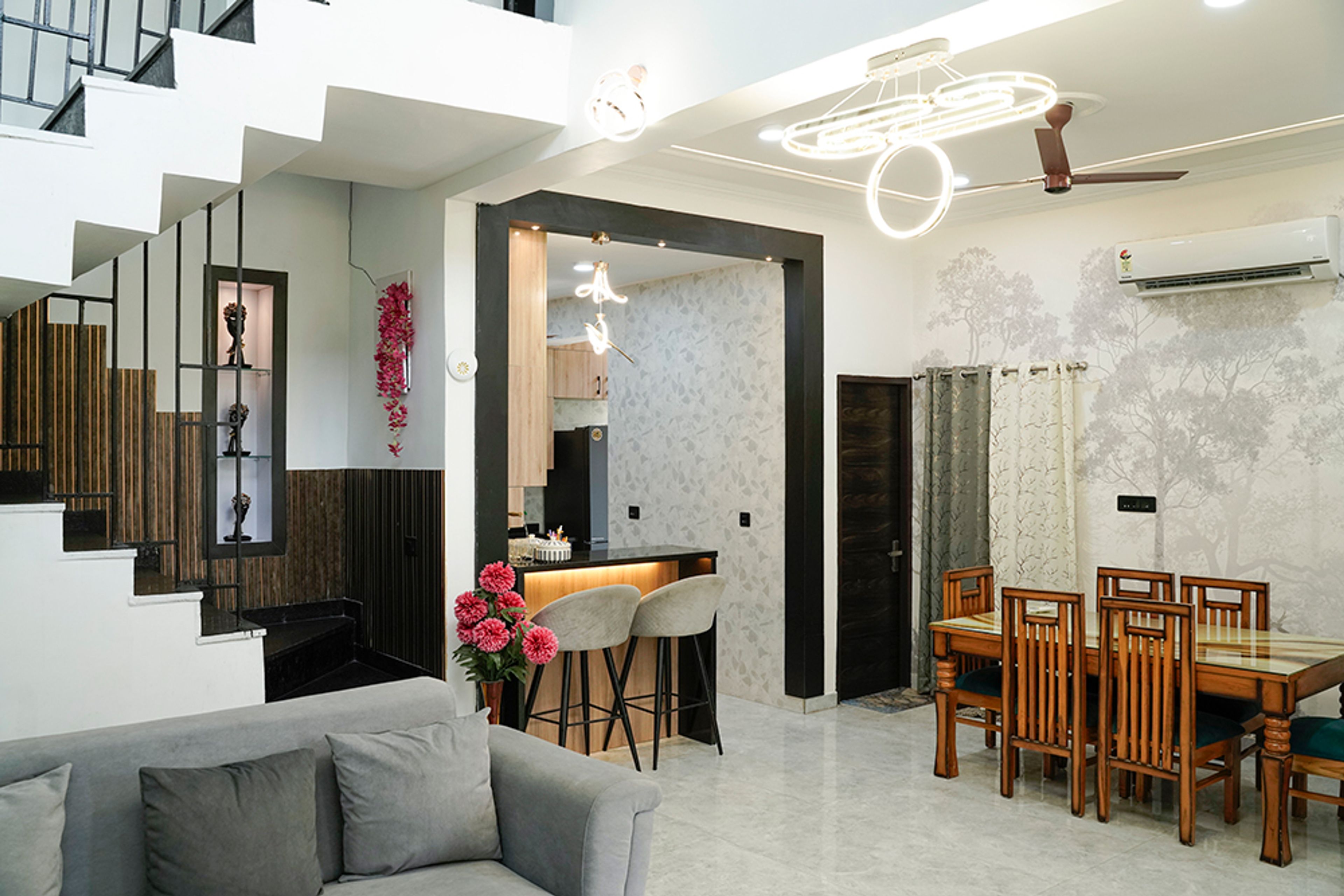 Dining Cum Living Room Design with Wooden Dining Table and Tree-Themed Wallpaper