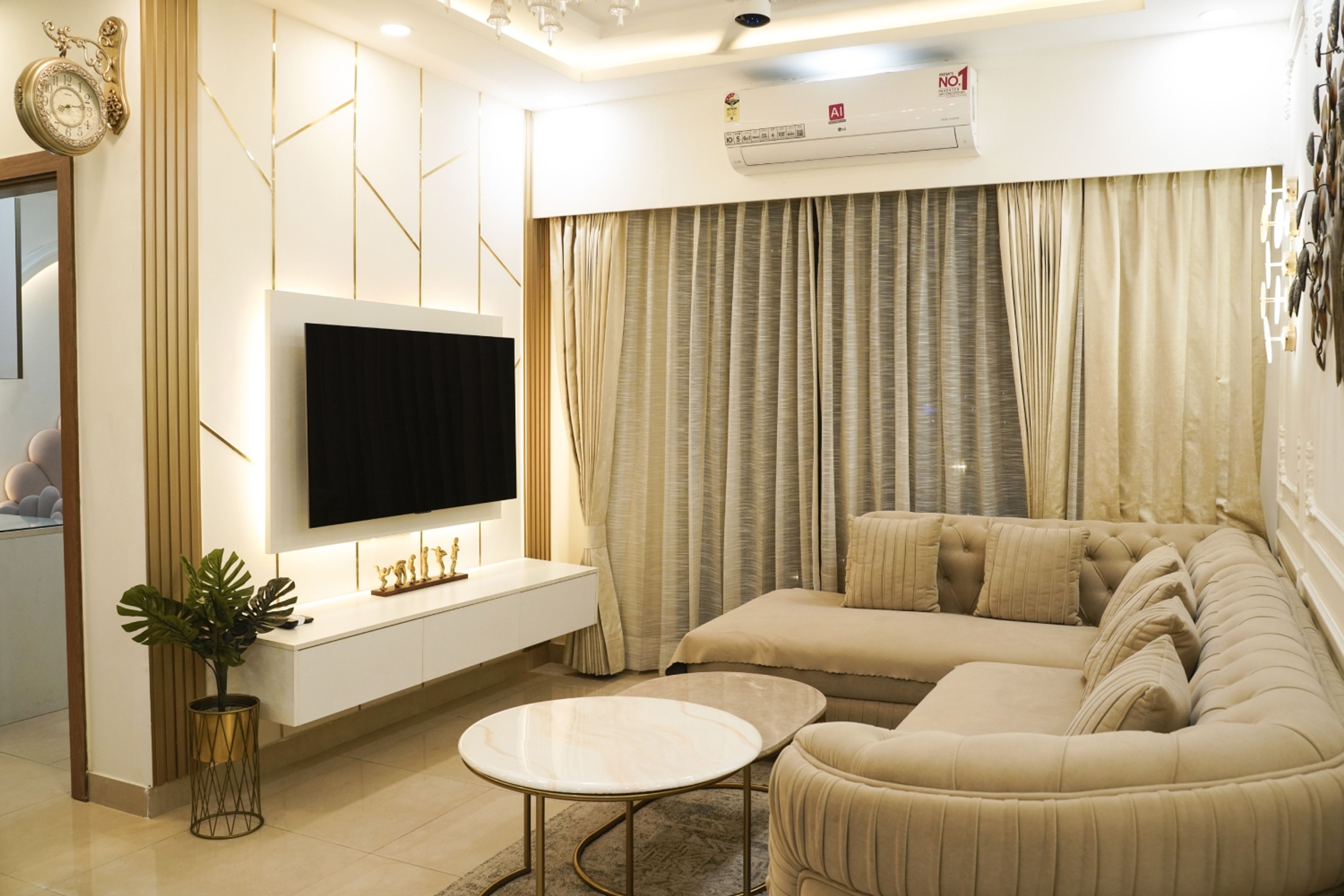 Living Room Design with Beige Tufted Sectional Sofa, Gold Accent Wall Panels, and Floating TV Unit