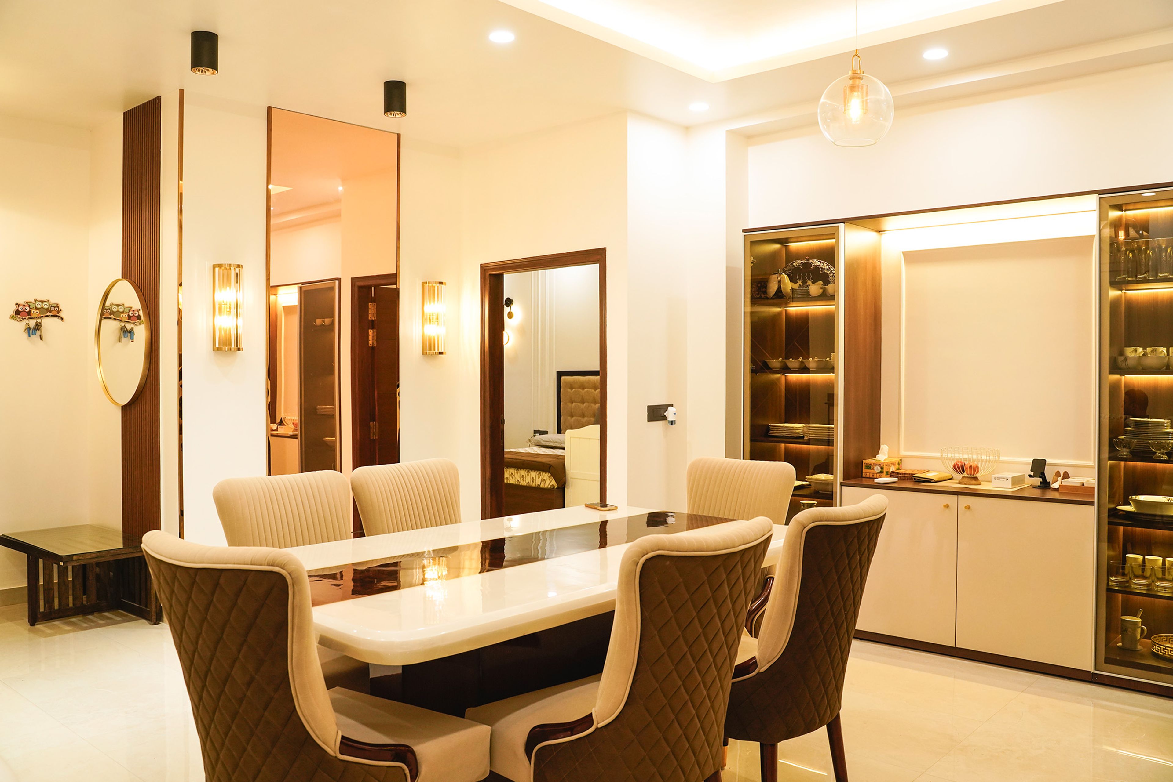 Dining Room Design with Cream Upholstered Dining Chairs, Wall Mirrors, and Crockery Unit with Glass Shelves