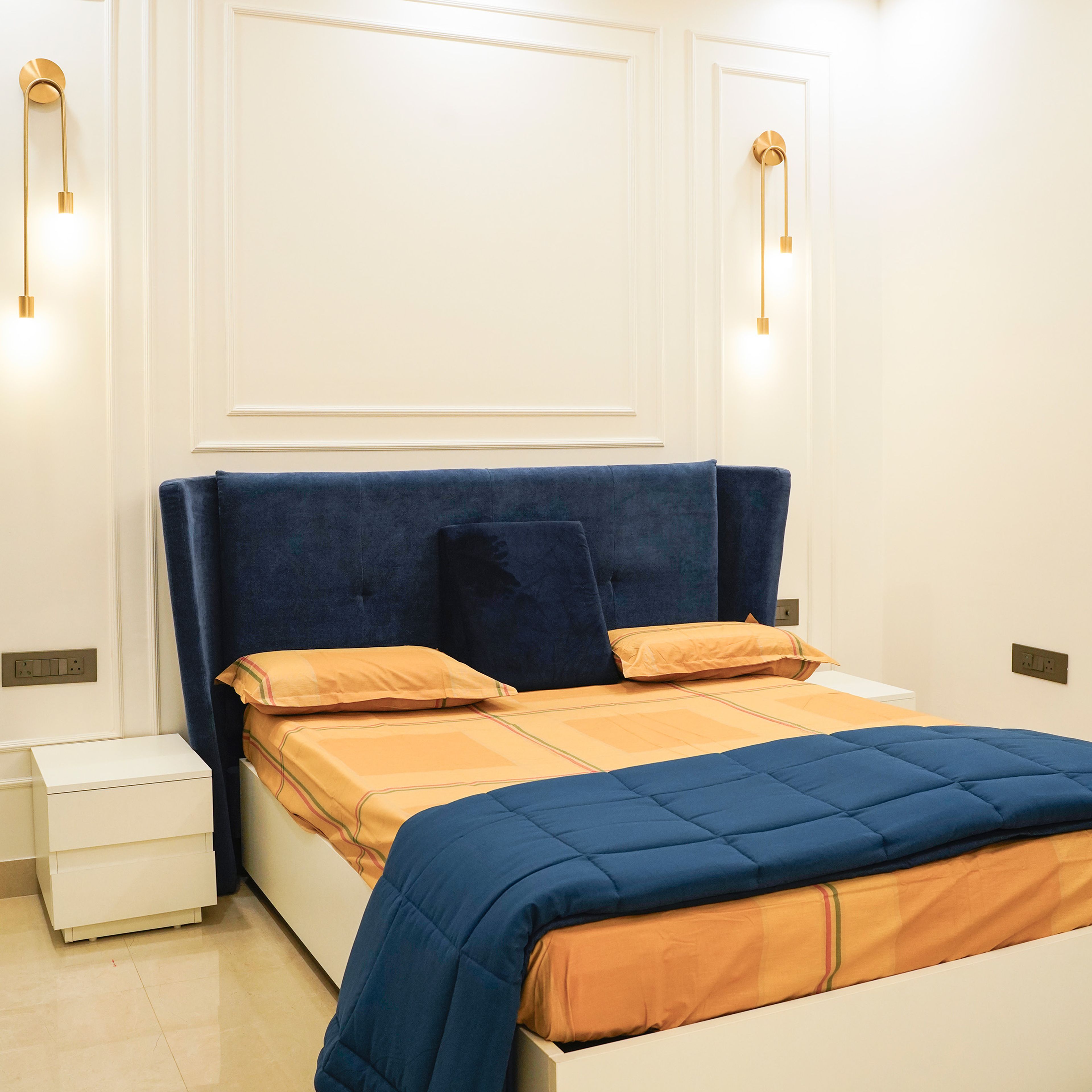 Master Bedroom Design with Blue Upholstered Bed, White Wall Panels, and Gold Wall Sconces