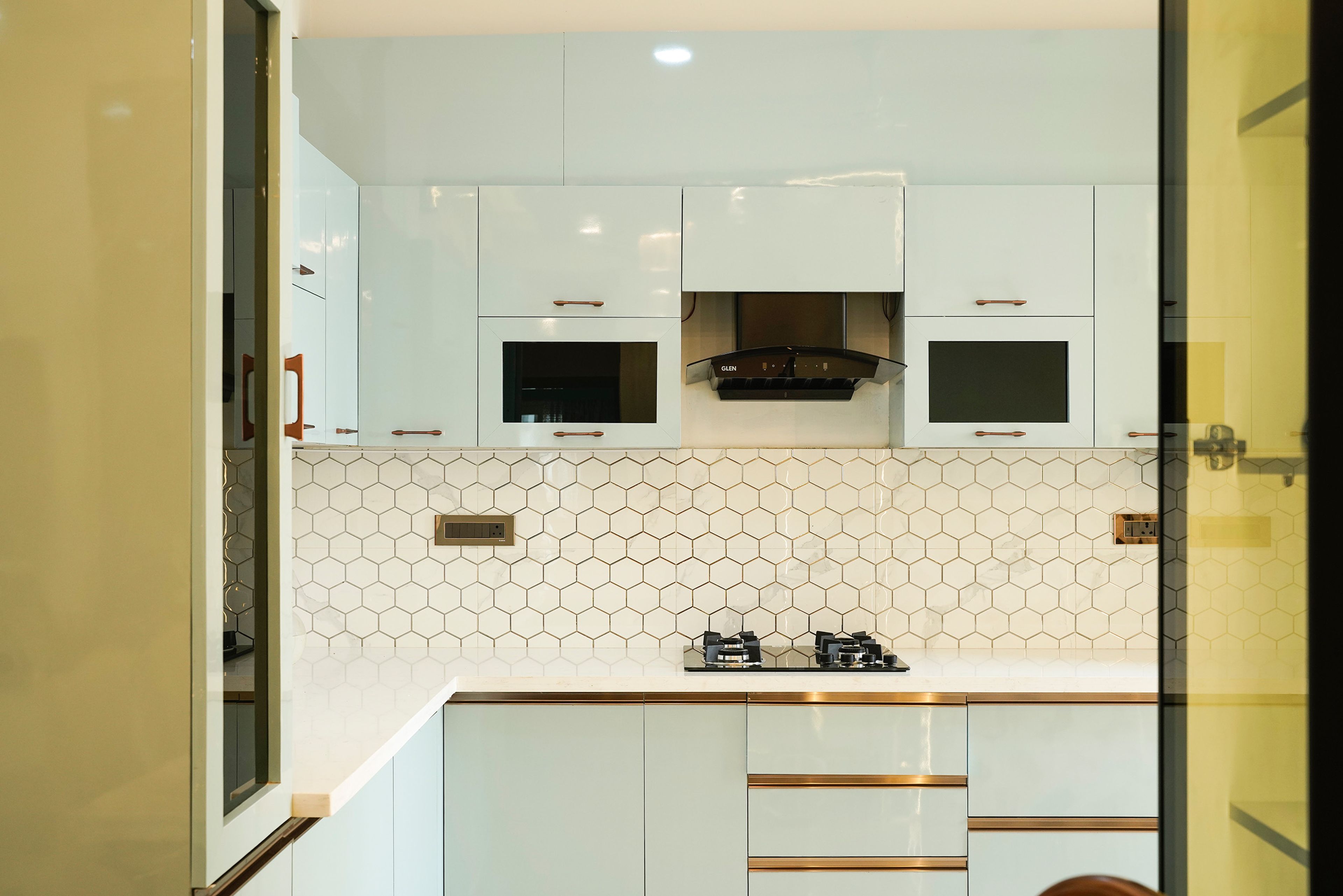 L-shaped kitchen design with white and black geometric pattern tiles backsplash