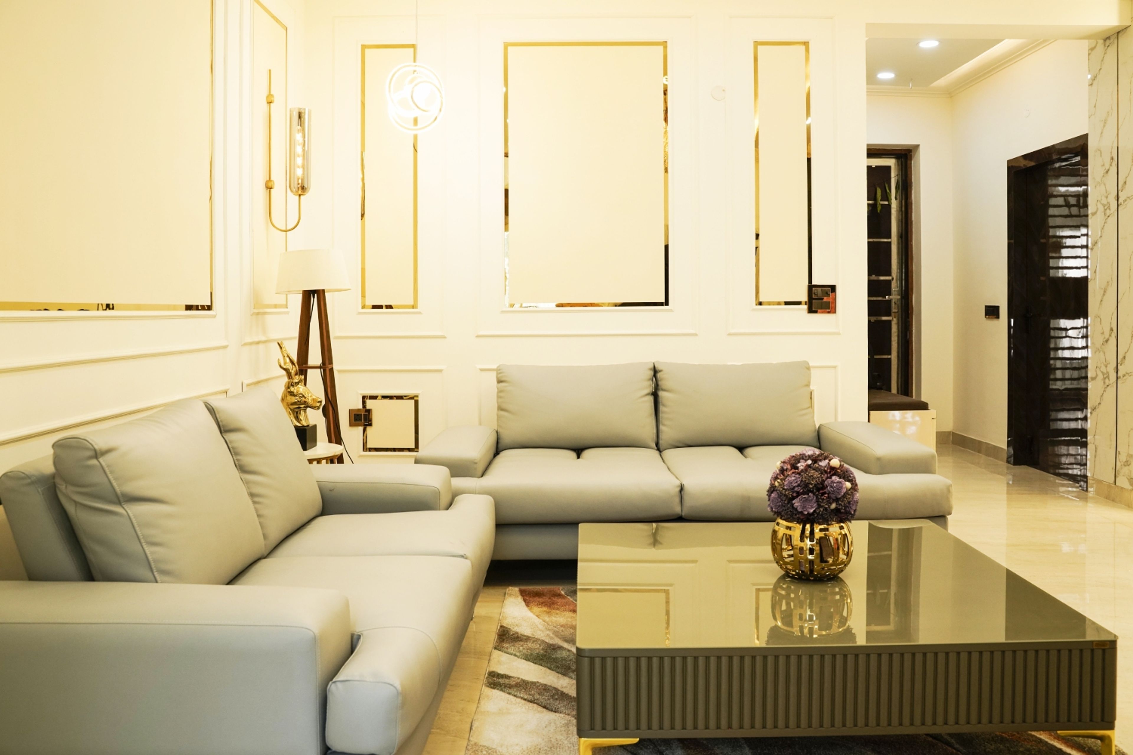 Living room design with light green sofas and cream wall with gold trims