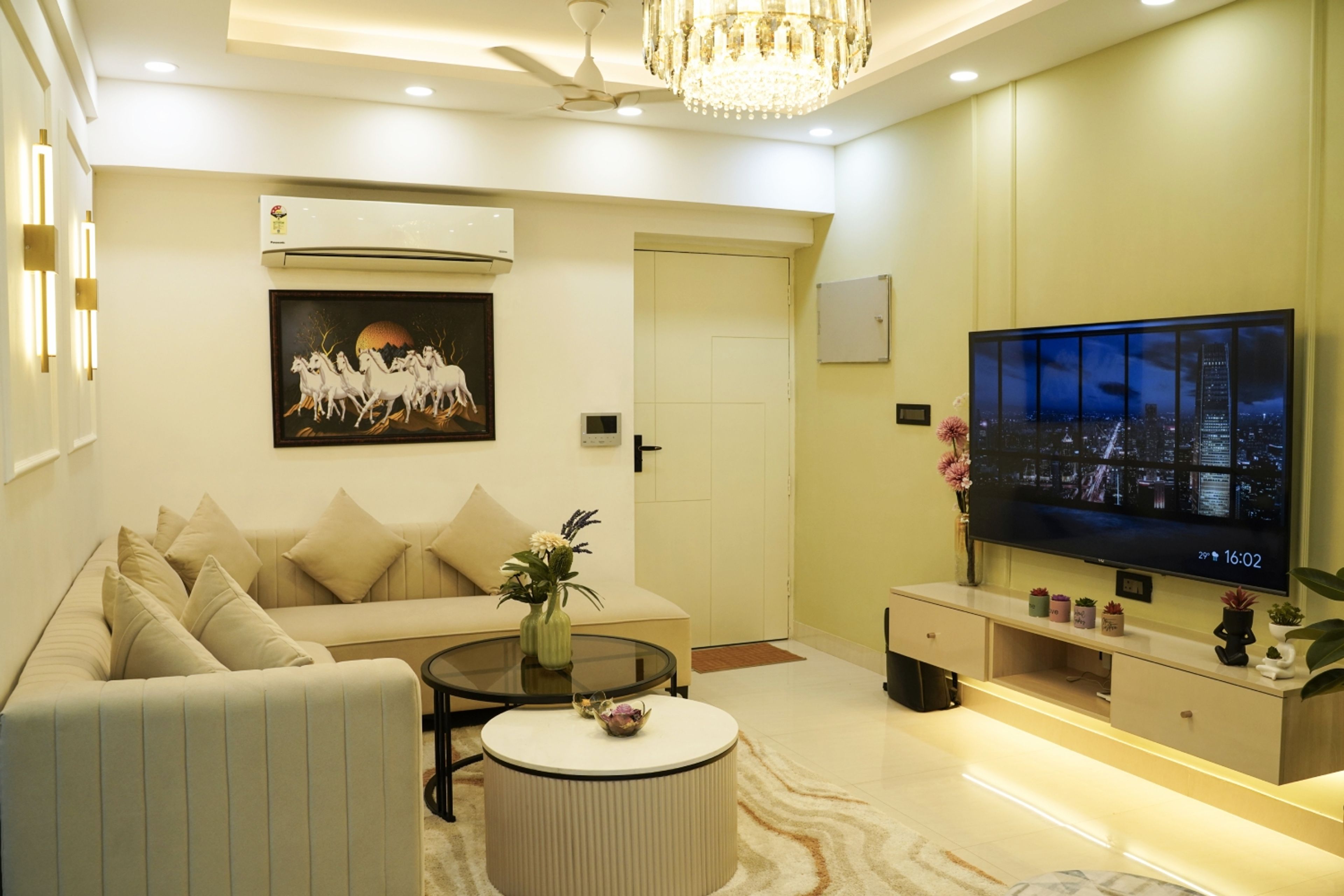 Living Room Design with Beige Sectional Sofa, Floating TV Unit with Drawer Storage, and Chandelier Ceiling Light