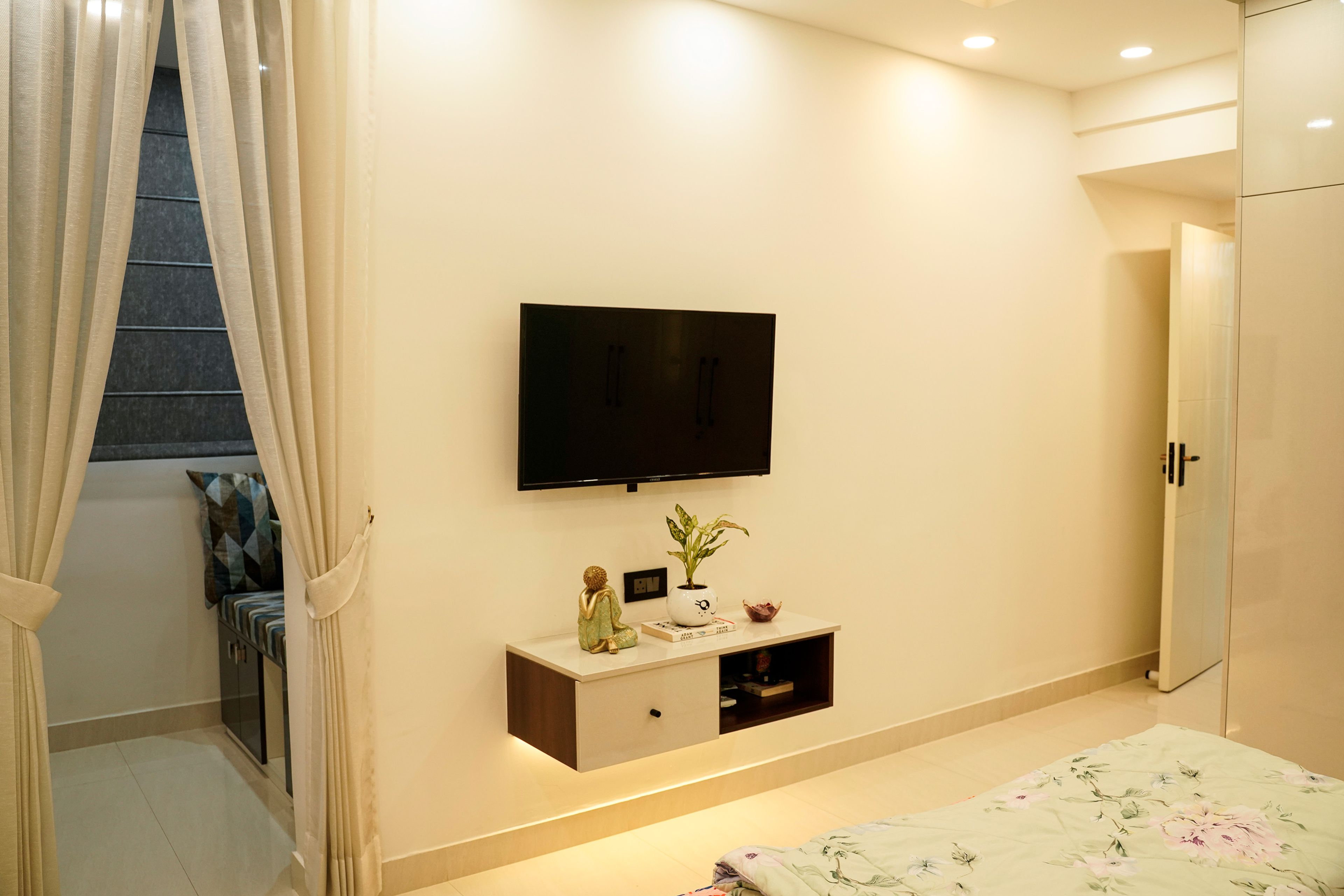 TV Unit Design with Wall-Mounted Screen and Floating White Drawer in Bedroom