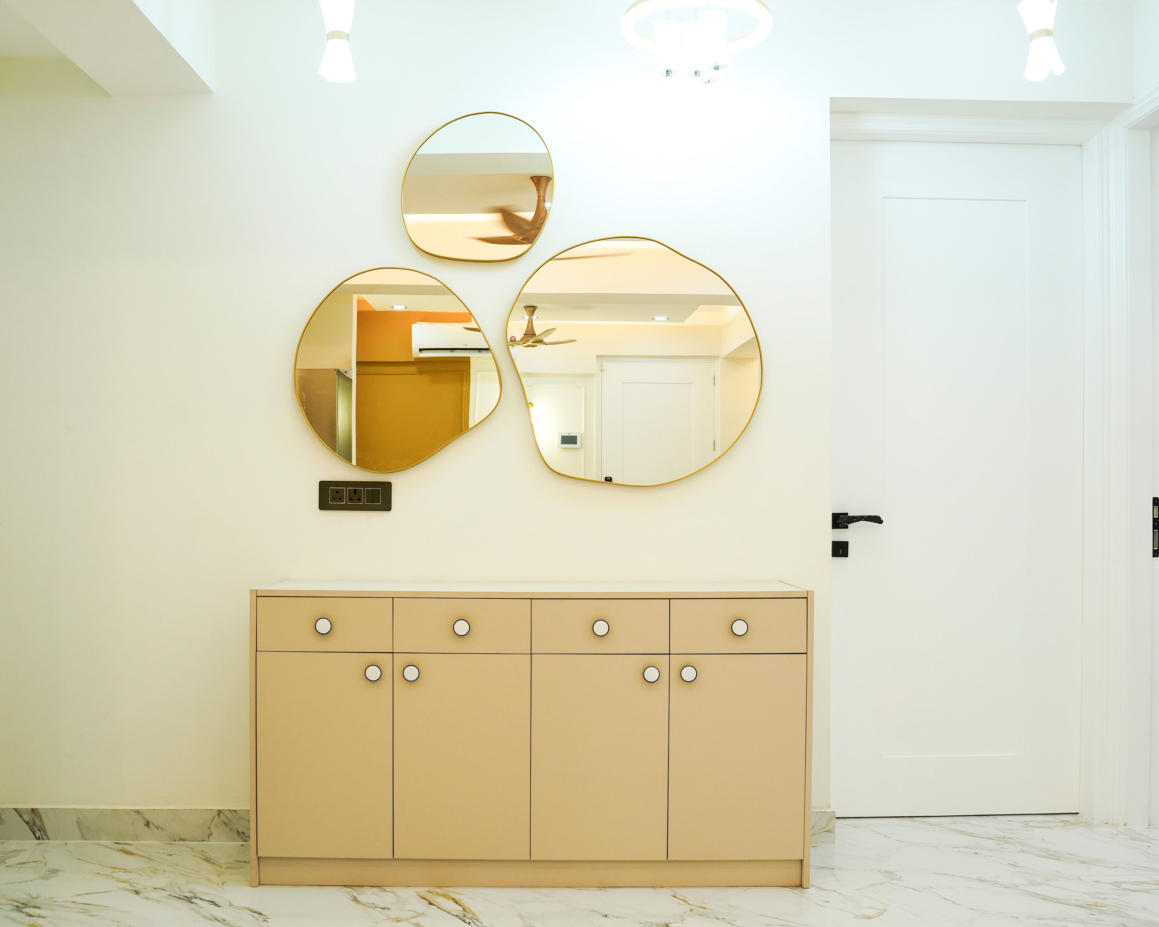 Foyer Design with Beige Storage Cabinet, Round Wall Mirrors, and Marble Flooring