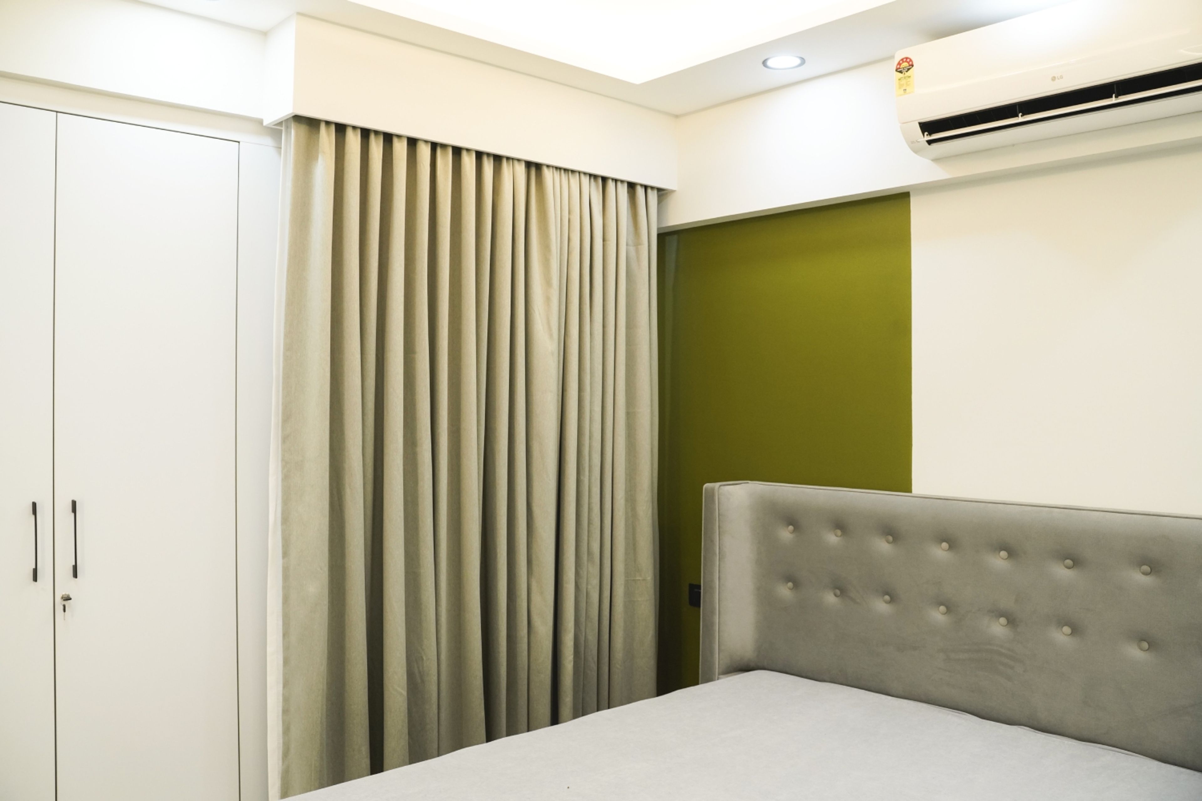 Guest Bedroom Design with Olive Green Accent Wall, Grey Upholstered Bed, and White Wardrobe