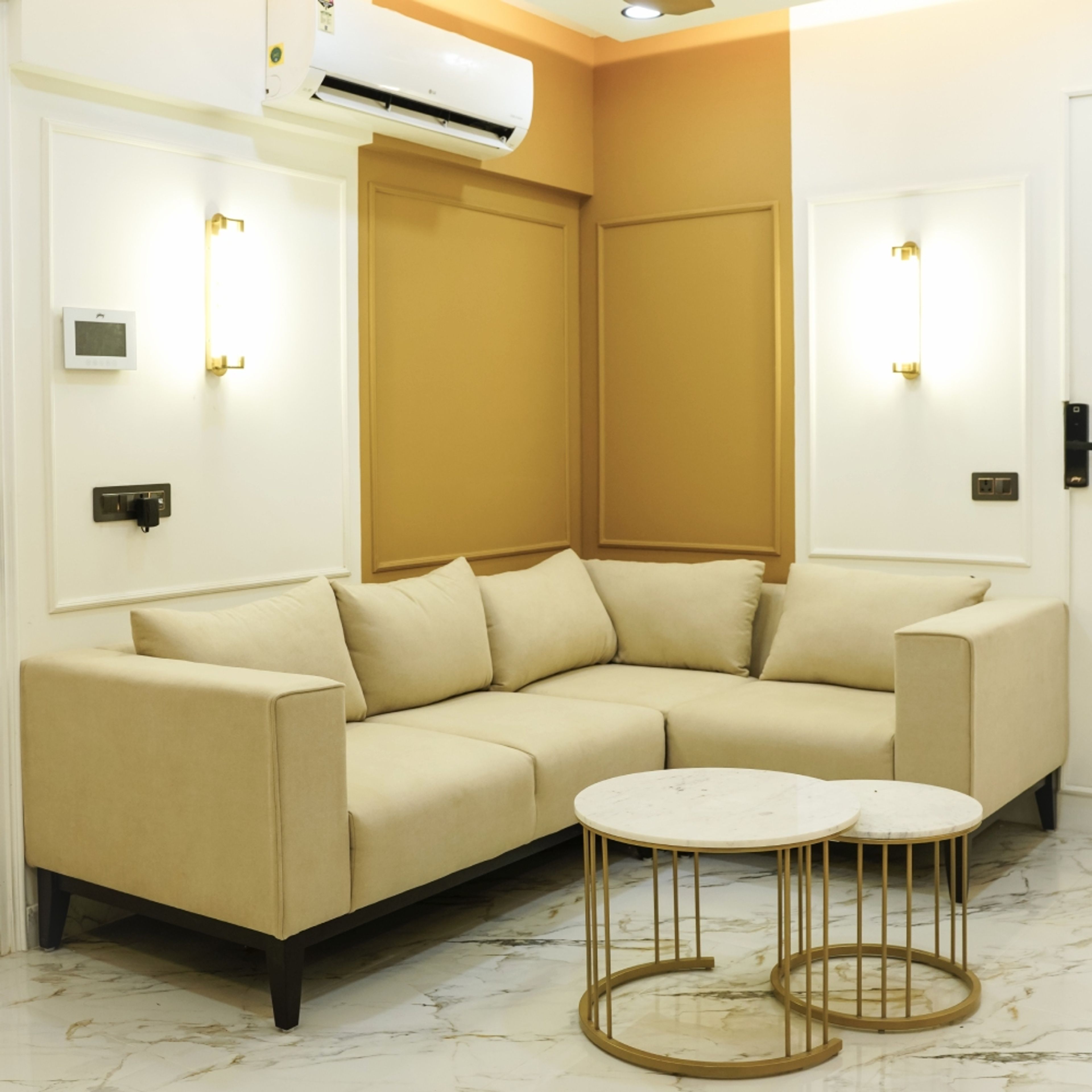 Living Room Design with Beige L-Shaped Sofa, Dual-Tone Wall Panels in White and Ochre, and Round Marble Coffee Tables