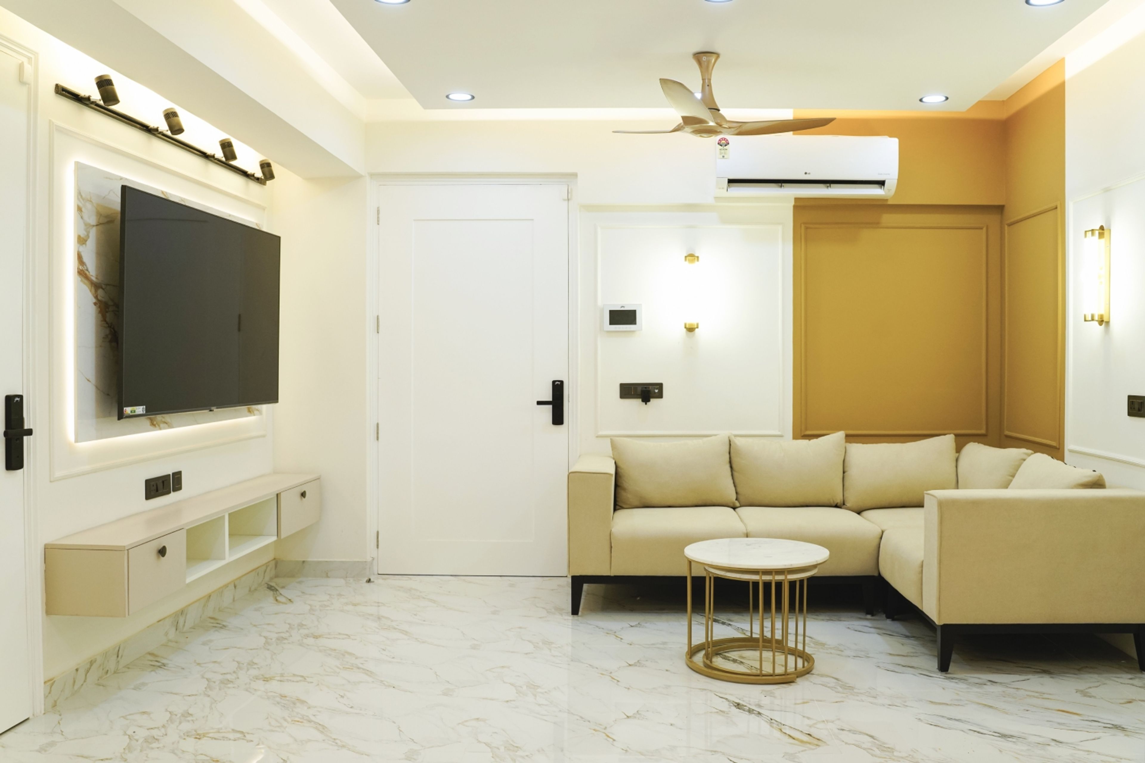 Living Room Design with Beige L-Shaped Sofa, Marble Flooring, and Floating TV Unit with White Panels