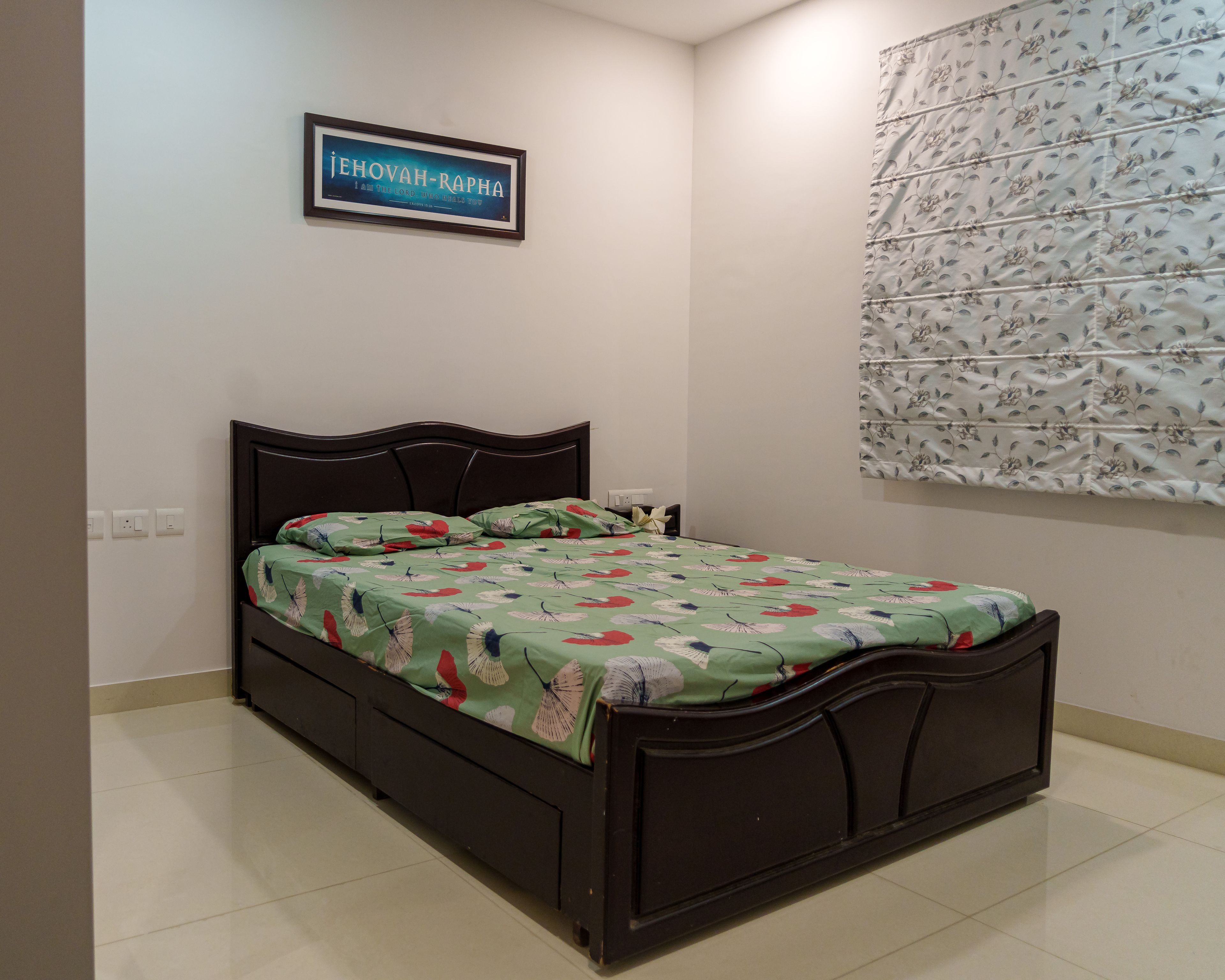 Guest Bedroom Design with Dark Wooden Bed, Floral Roman Blind, and White Walls