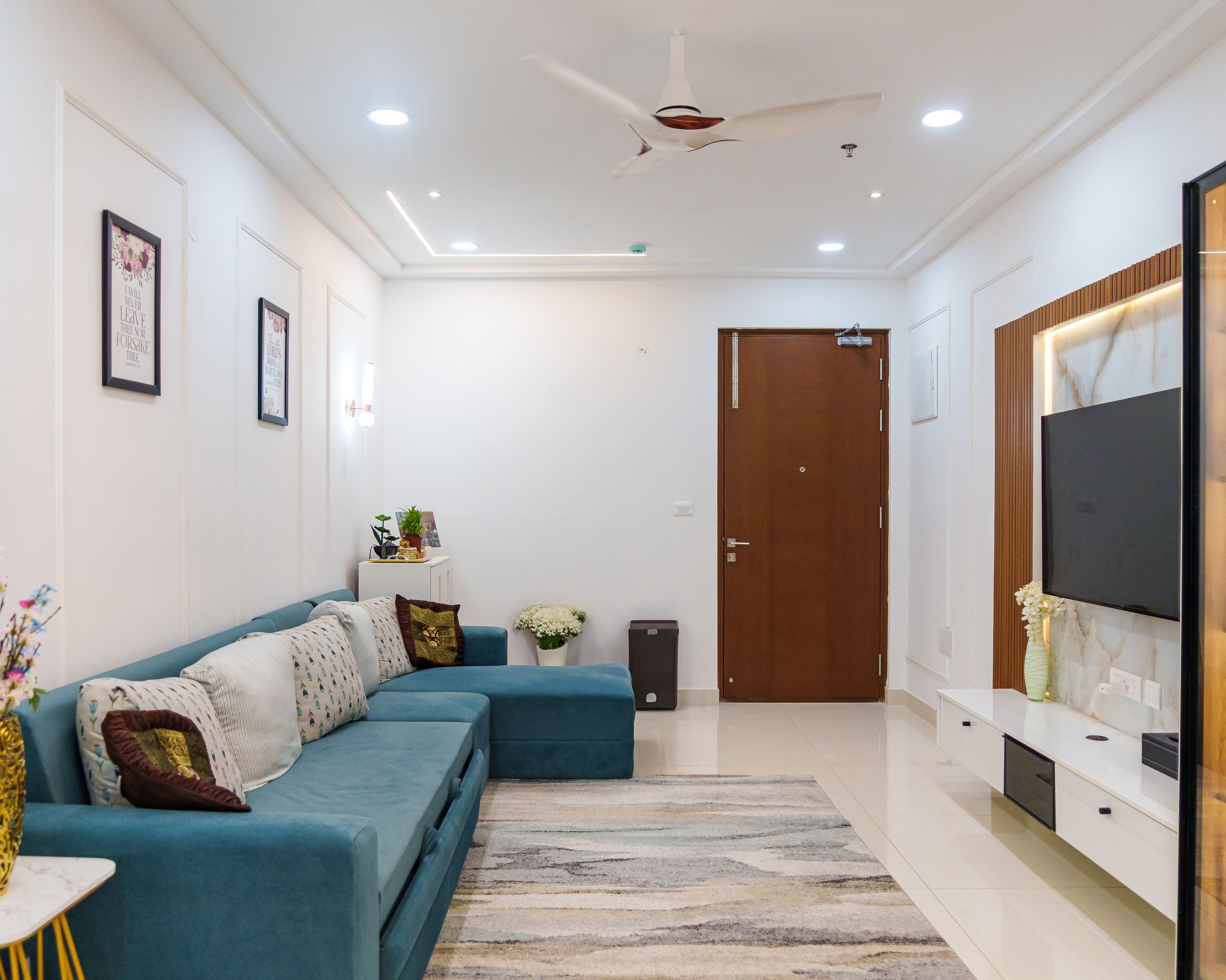 Living Room Design with Teal L-Shaped Sofa, Wall-Mounted TV Unit with Marble Panel, and White Entrance Door