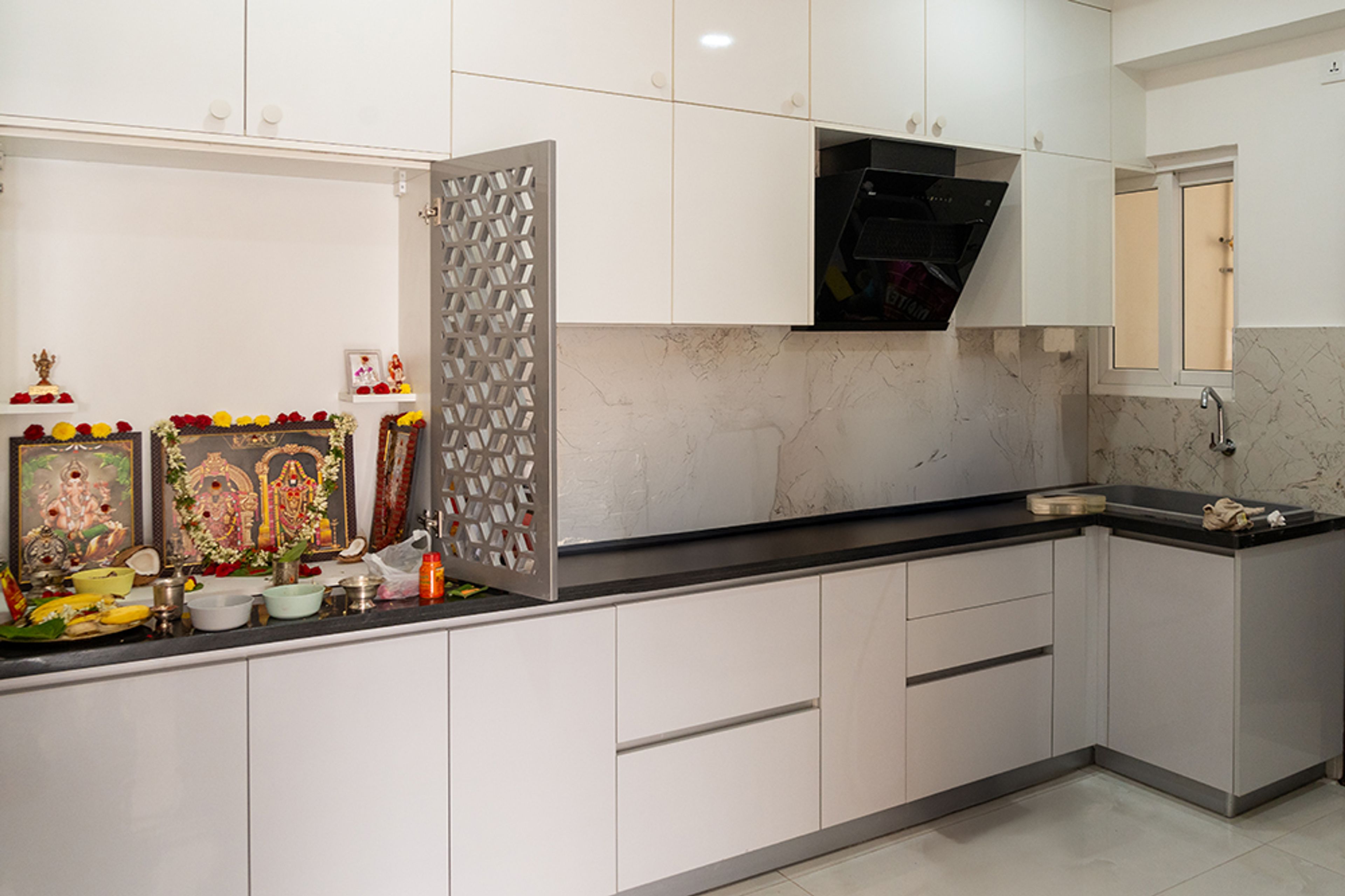 L-Shaped Kitchen Design White Units and Lattice Patterned Door Pooja Unit