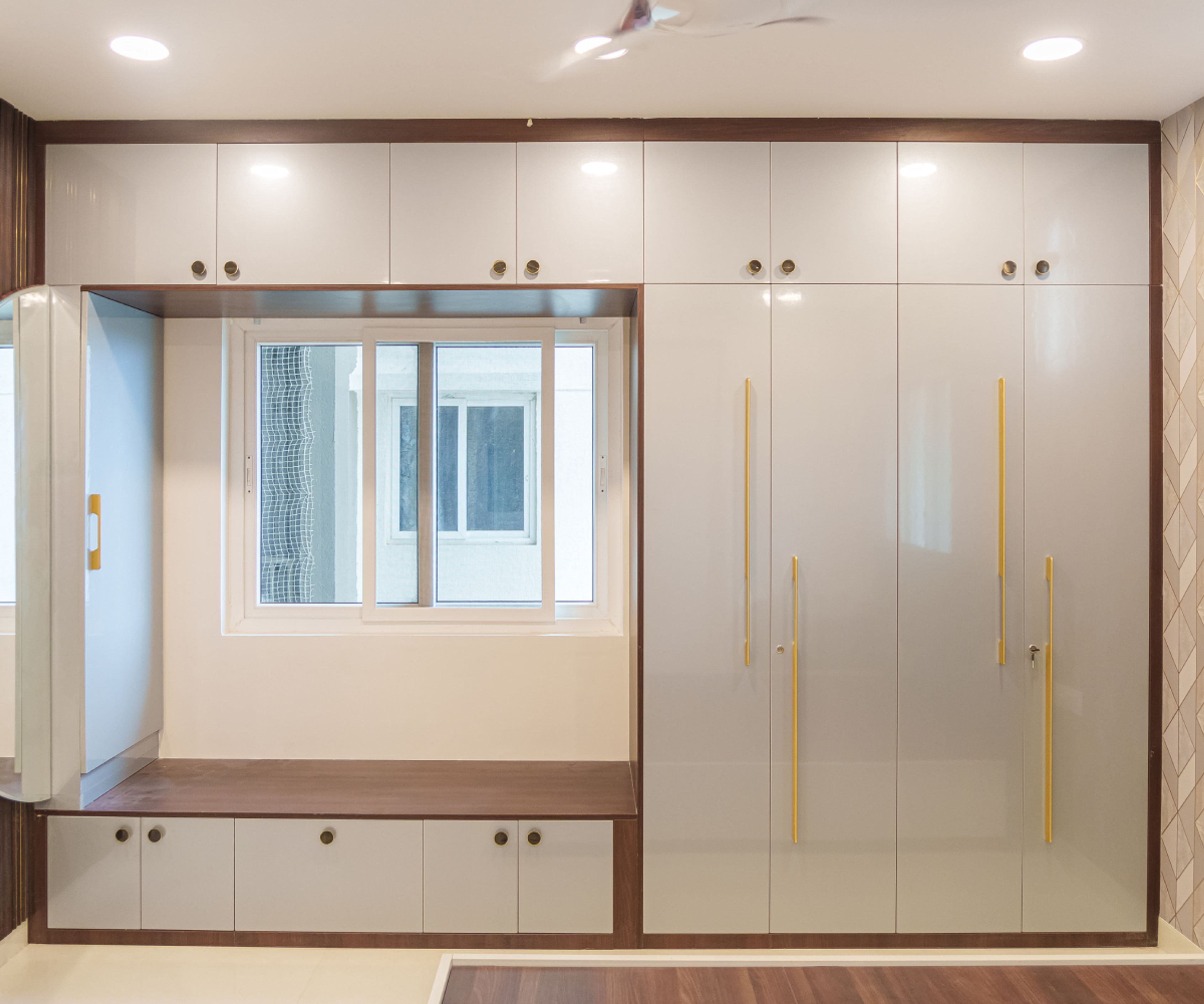 Glossy Off-White Swing Wardrobe Design With Overhead Storage and a Built-In Wooden Bench