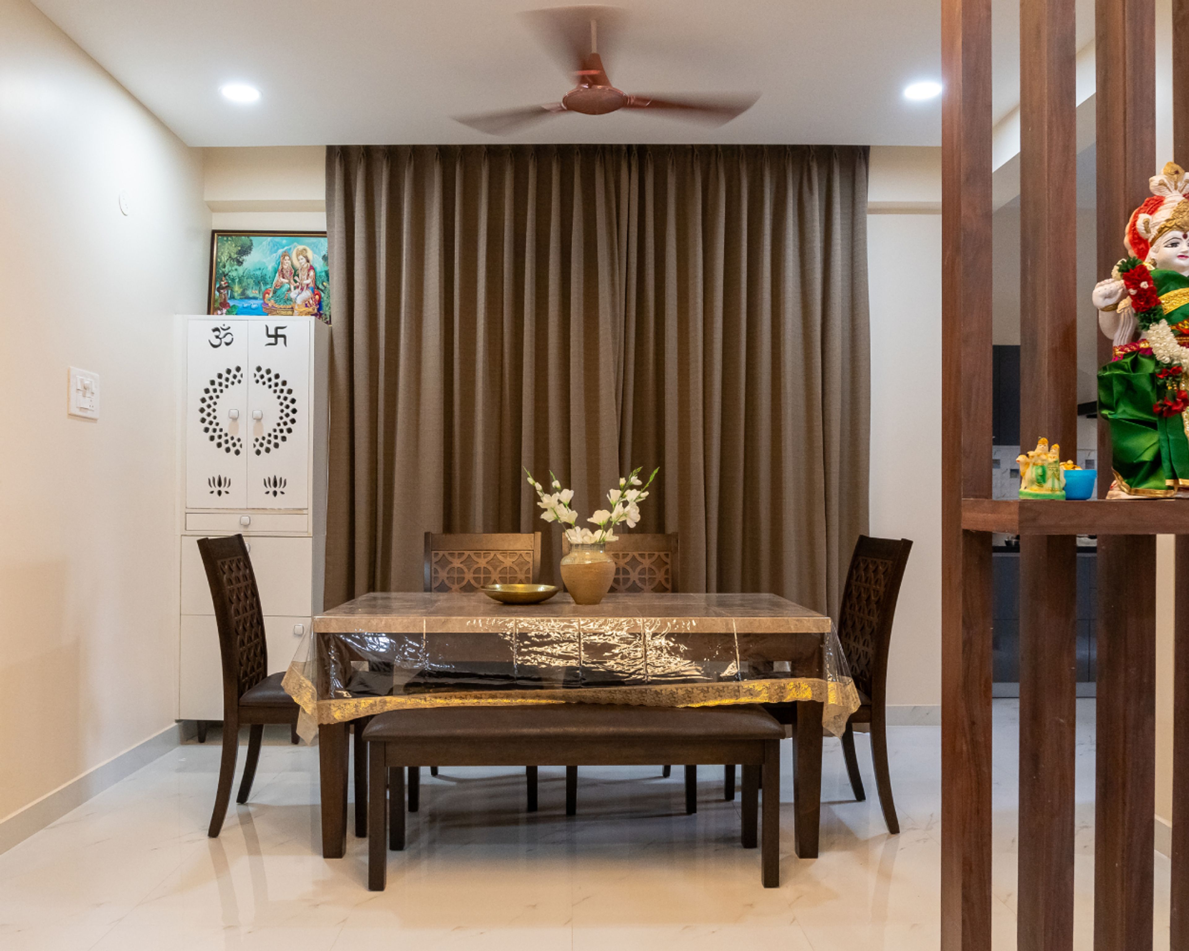 6-Seater Dining Room Design with Wooden Chair and Cushioned Seating Bench and White Closed Pooja Unit