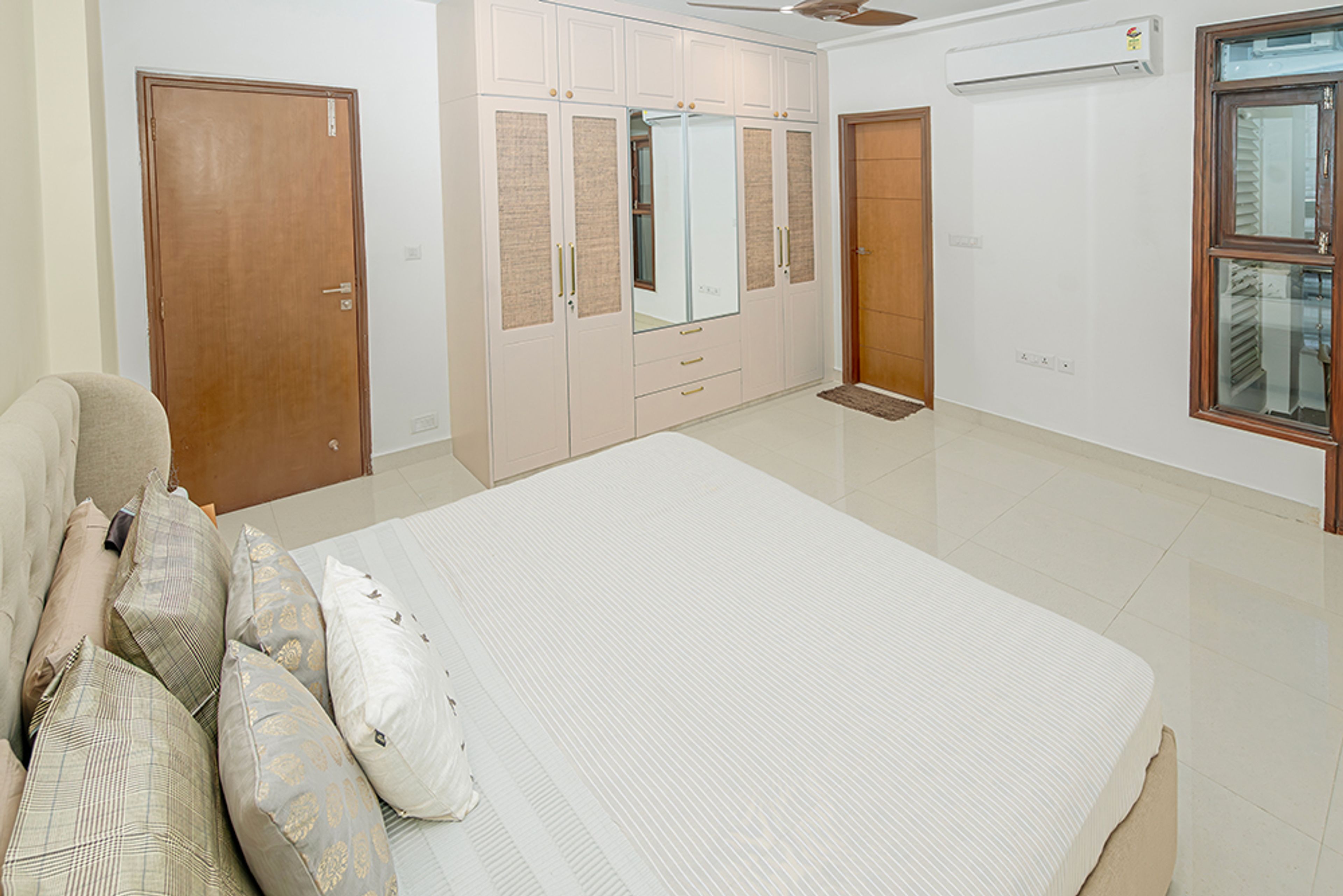 Bedroom Design with Brown Tufted Headboard Bed and 4-Door Swing Wardrobe with Attached Mirror