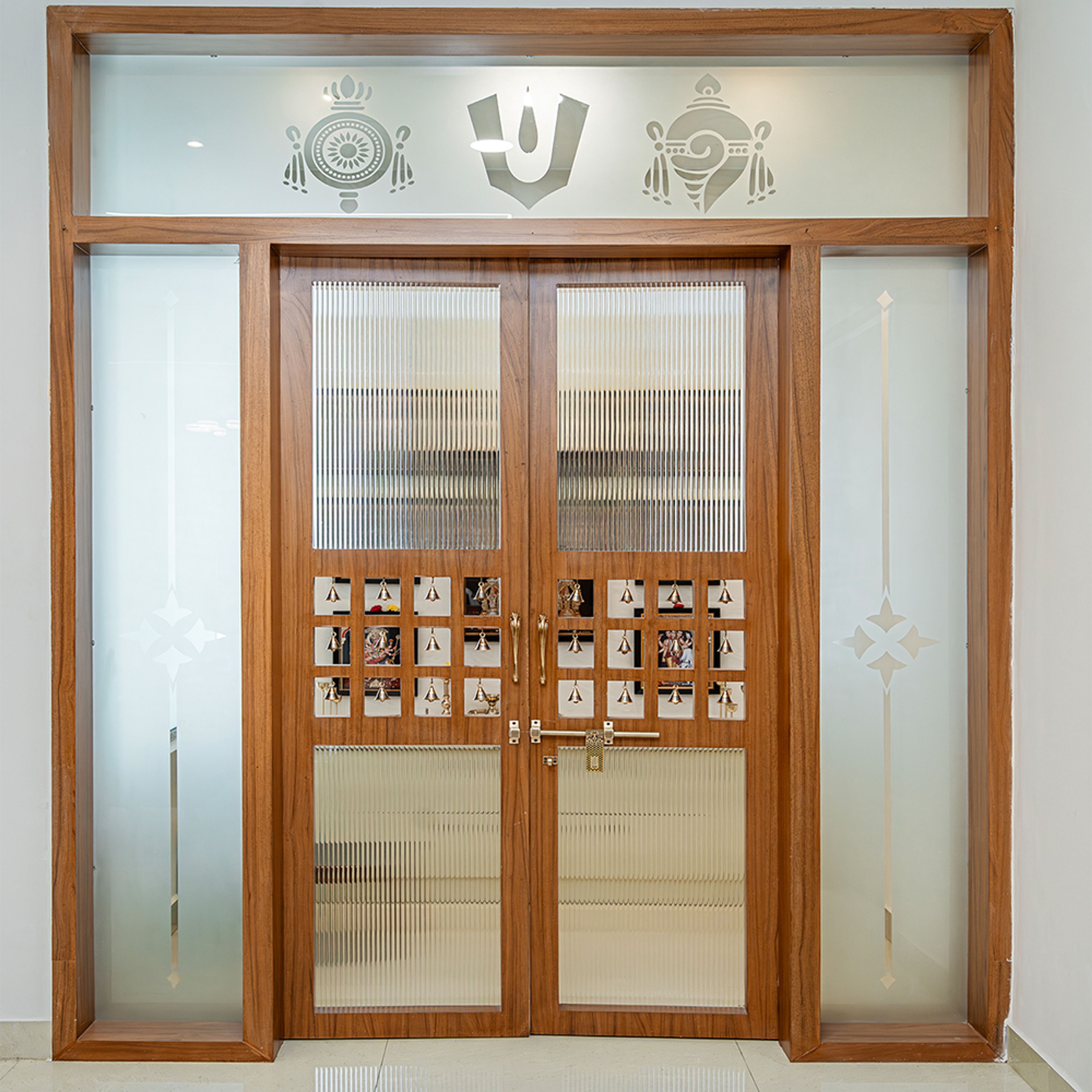 Pooja Door With Frosted Glass, Wooden Frame, Etched Symbols, Brass Handles, And Decorative Bells Inset
