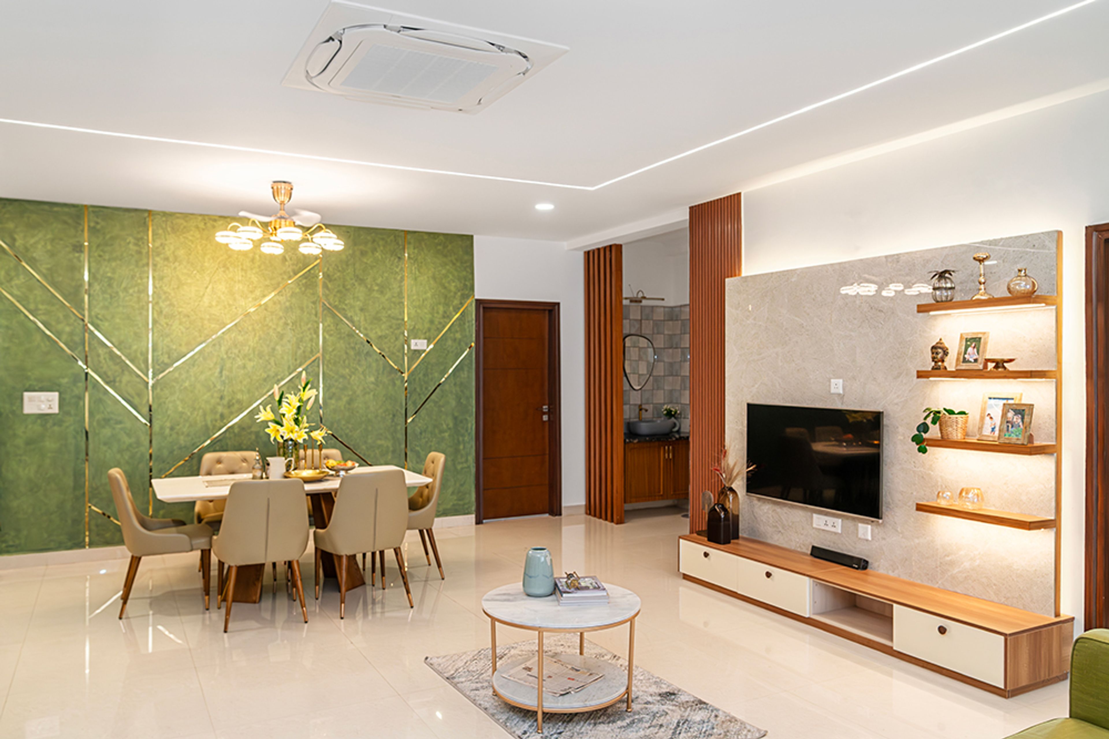 Living Room Design with TV Unit with Wooden Floating Shelves, Dining Table and Green Wall with Gold Inlays