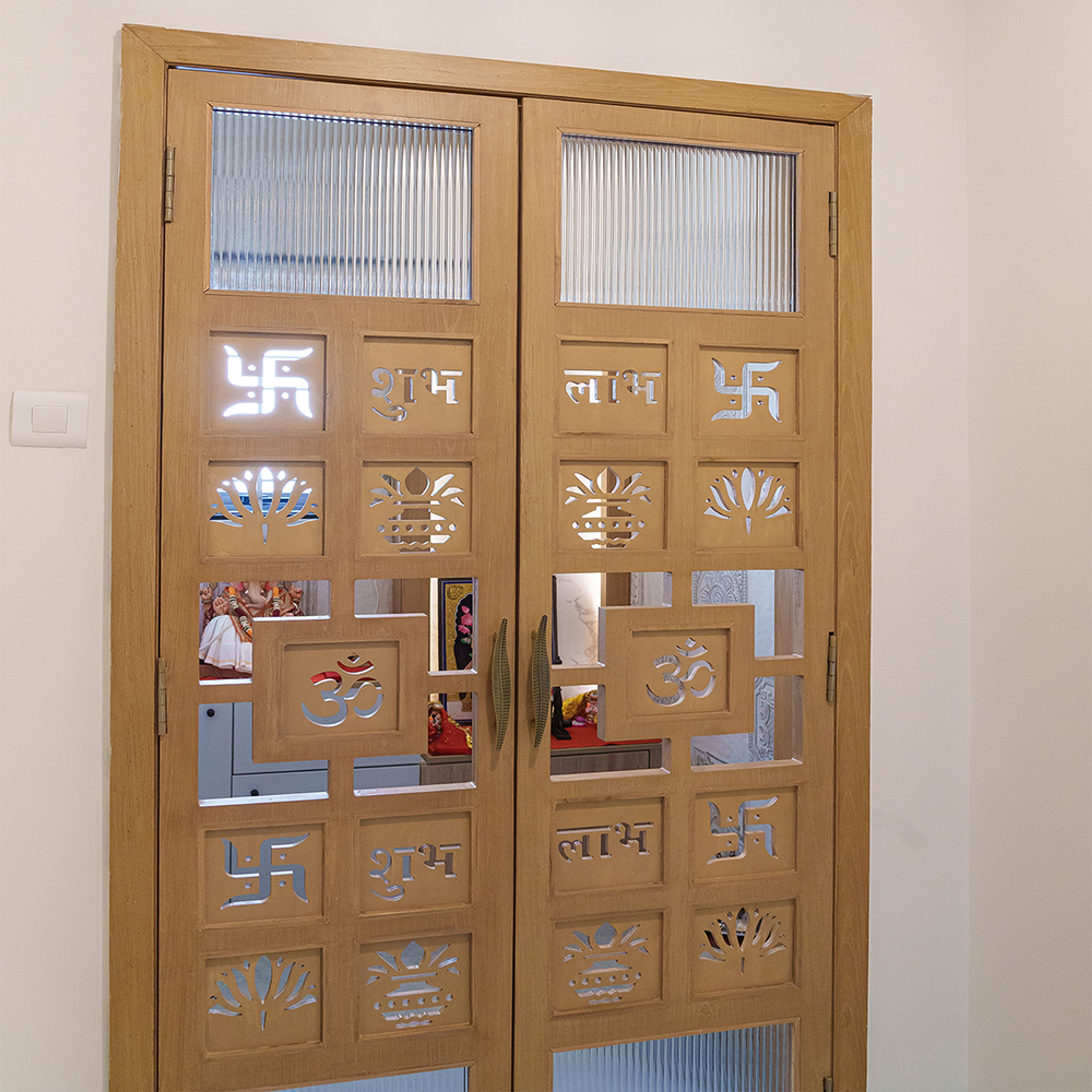 Double Swing Pooja Door Design with Carved Wooden Panels and Religious Symbol Cutouts