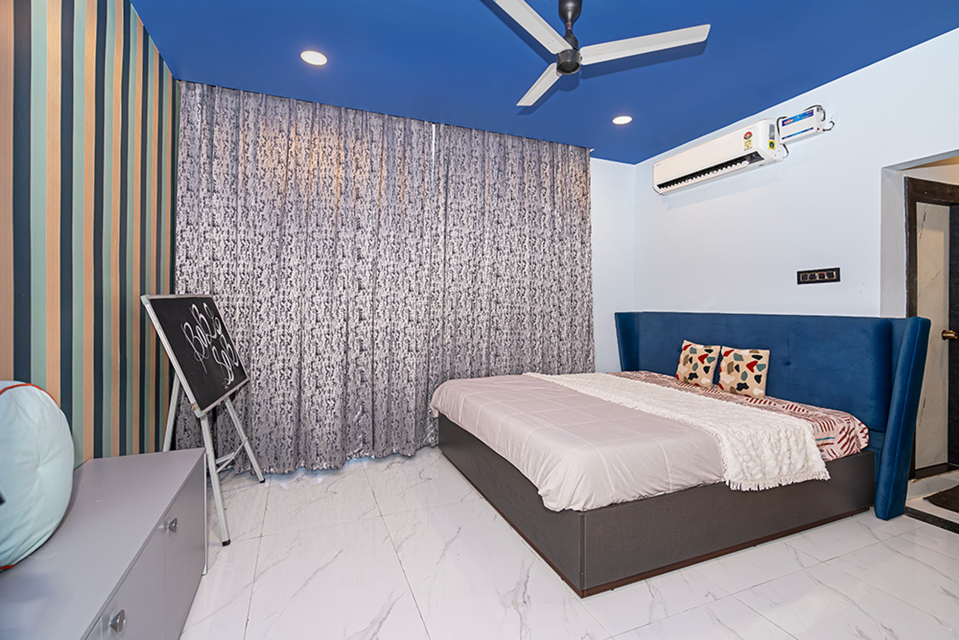 Bedroom Design with Blue Tufted Headboard Bed and Vertical Stripes Wallpaper