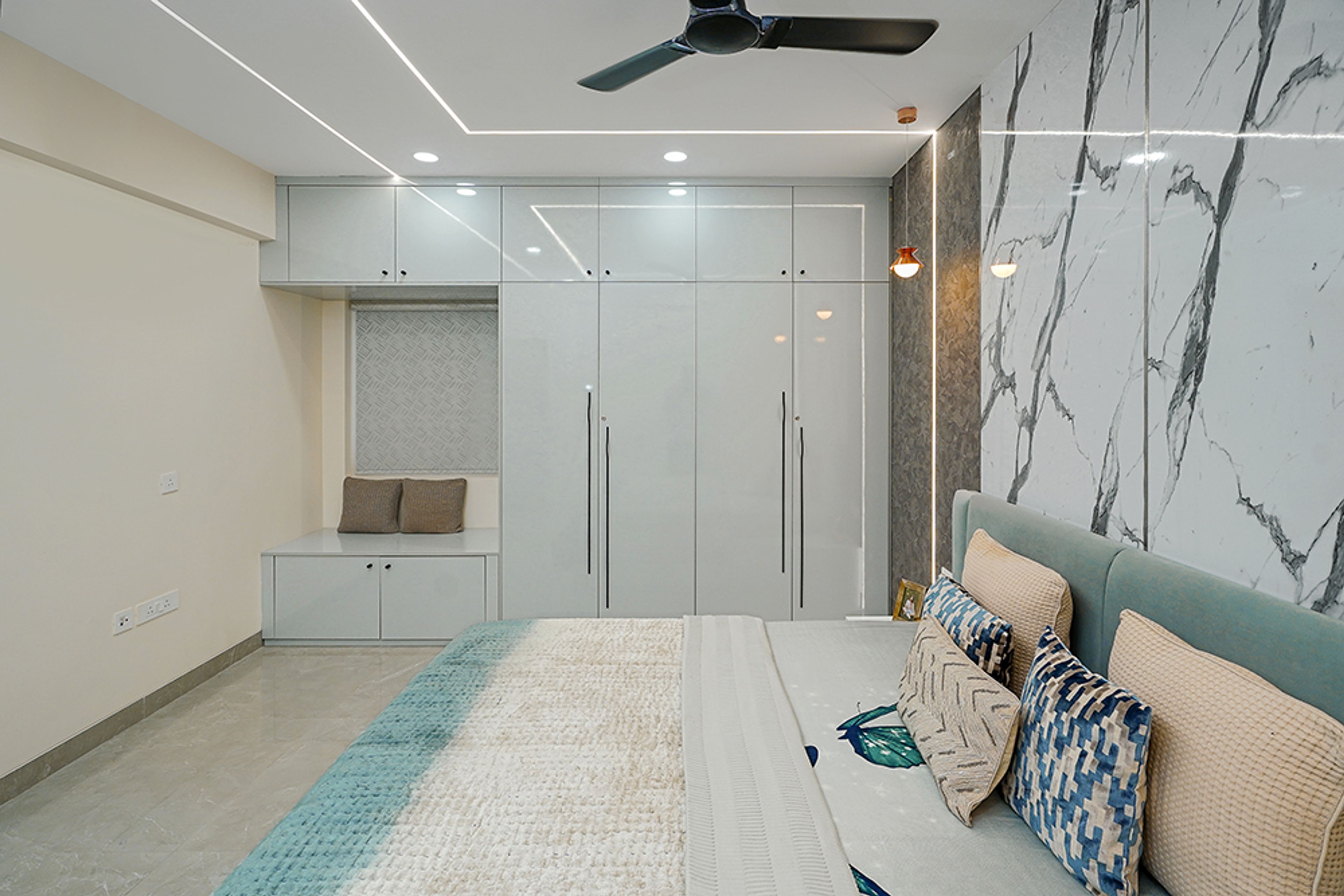 Bedroom Design with 4-Door Light Blue Swing Wardrobe and Marble Patterned Accent Wall