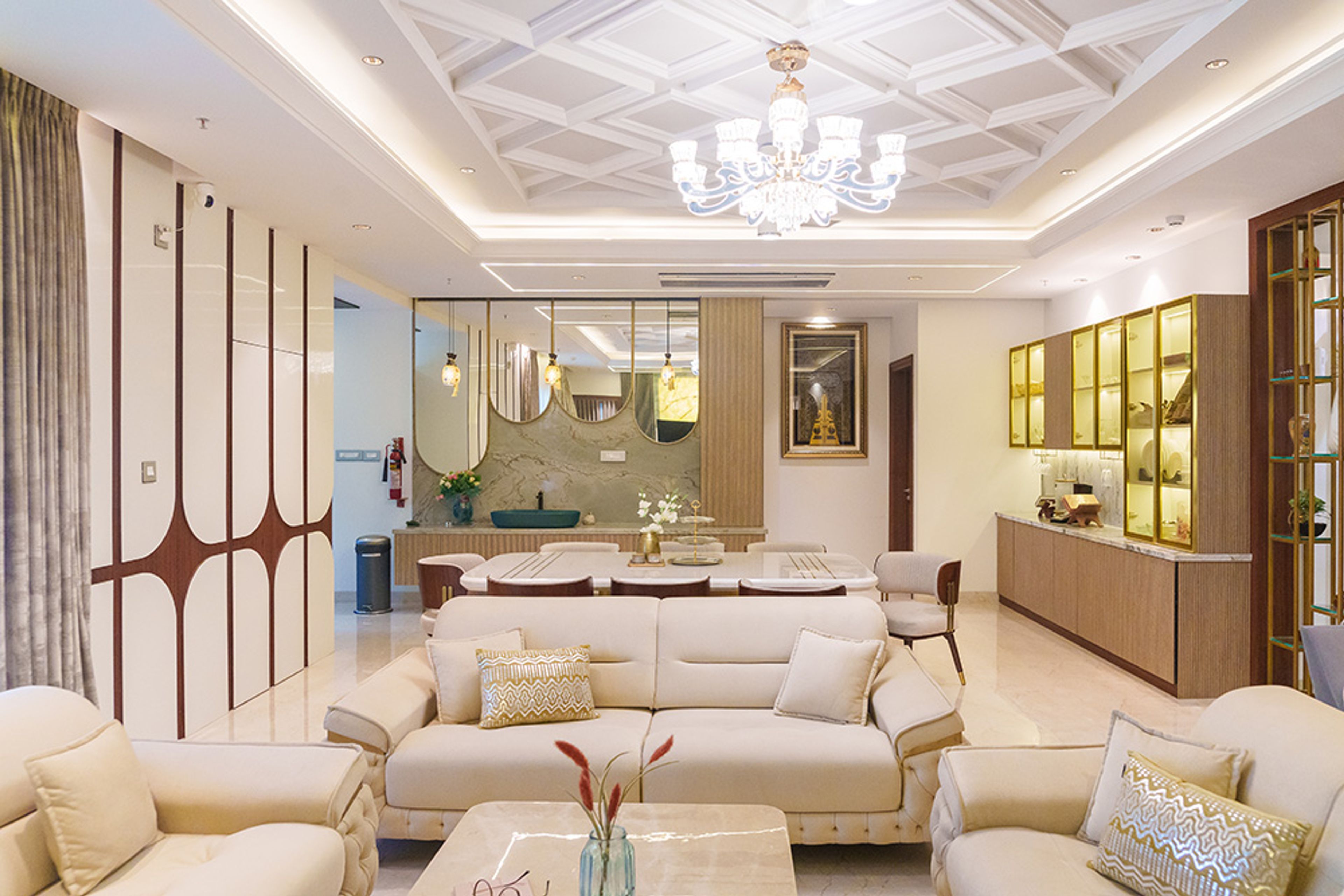 Living and Dining Room Design with Cream Upholstered Sofas, Geometric Wood Accent Wall, Gold-Backlit Display Cabinets, and Marble Dining Table
