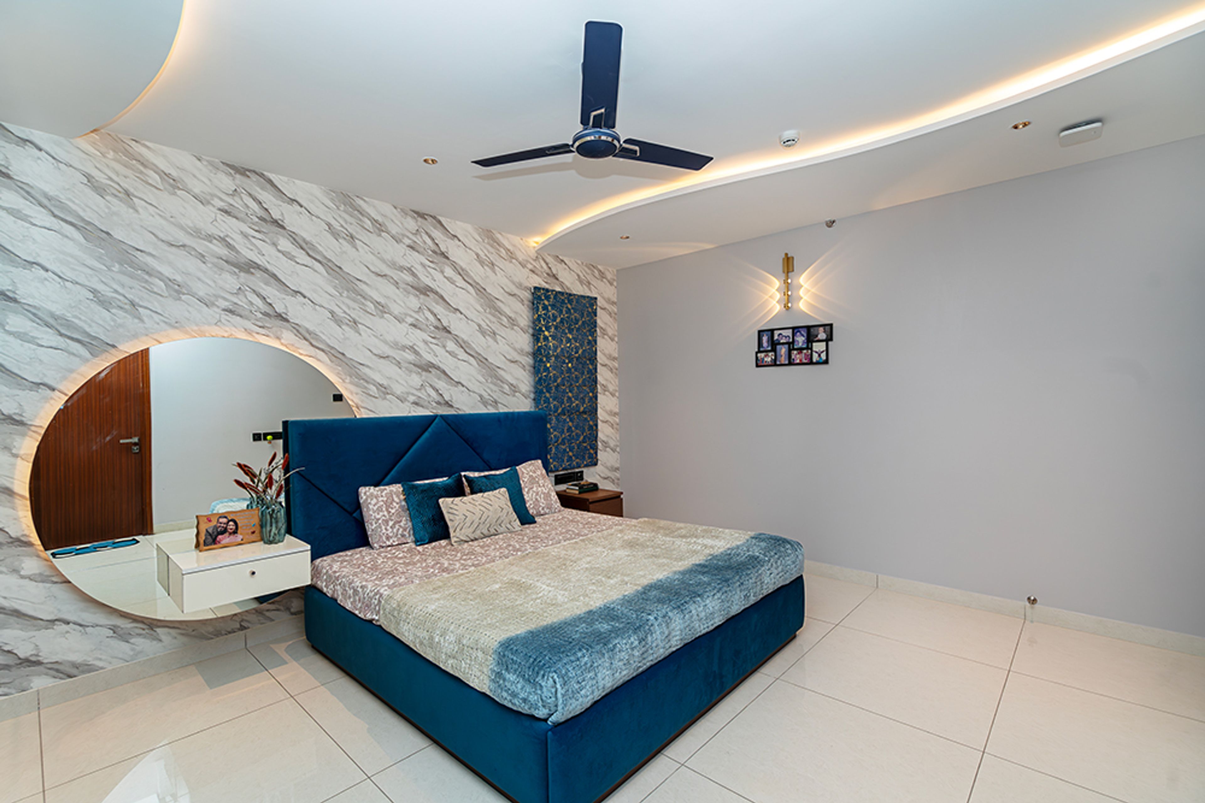 Bedroom Design with Marble Patterned Wall and Tufted Headboard Wall with Wall-Mounted Round Mirror