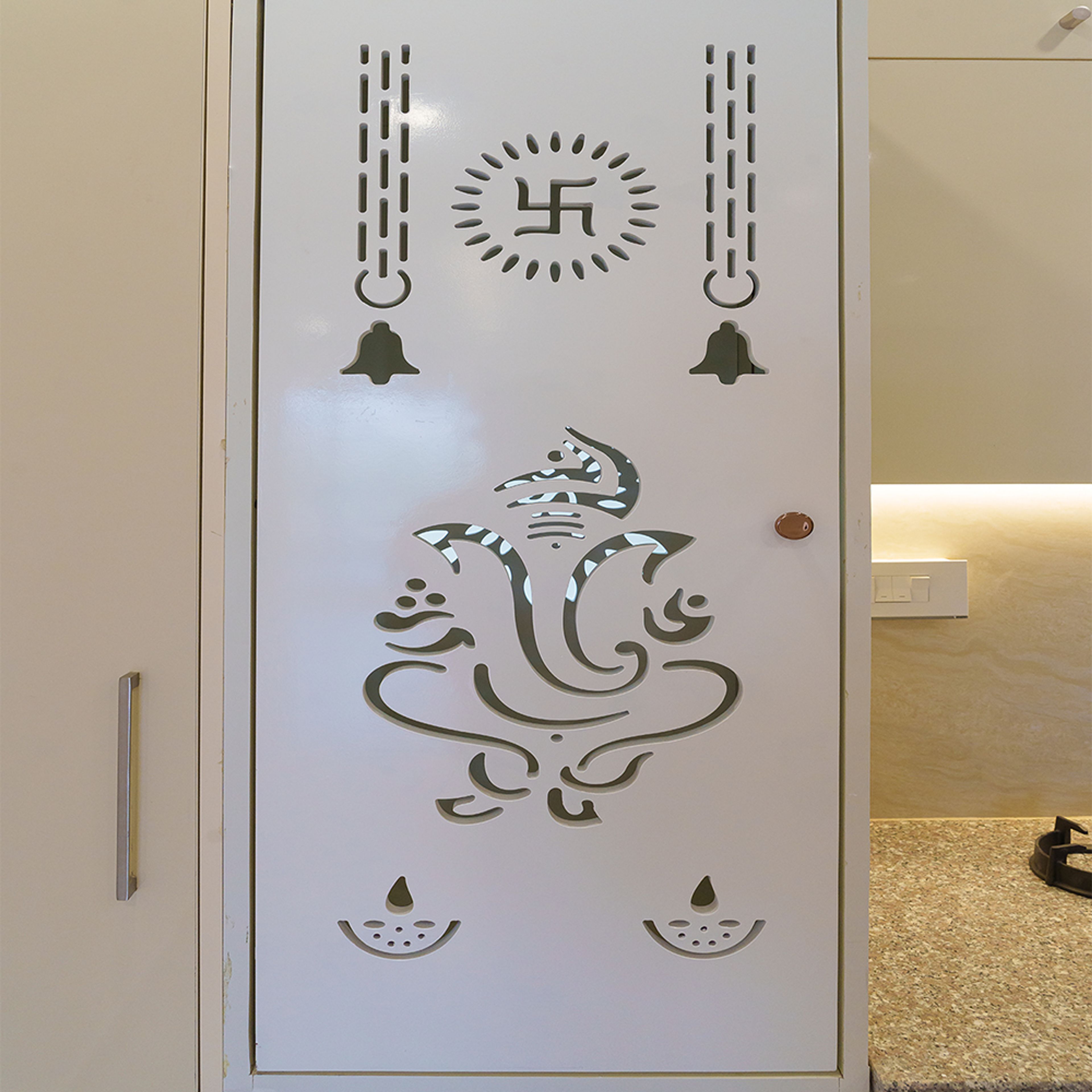 L-Shaped Kitchen Design with Laser-Cut White Pooja Unit with Ganesha, Bells, Diya, and Swastika