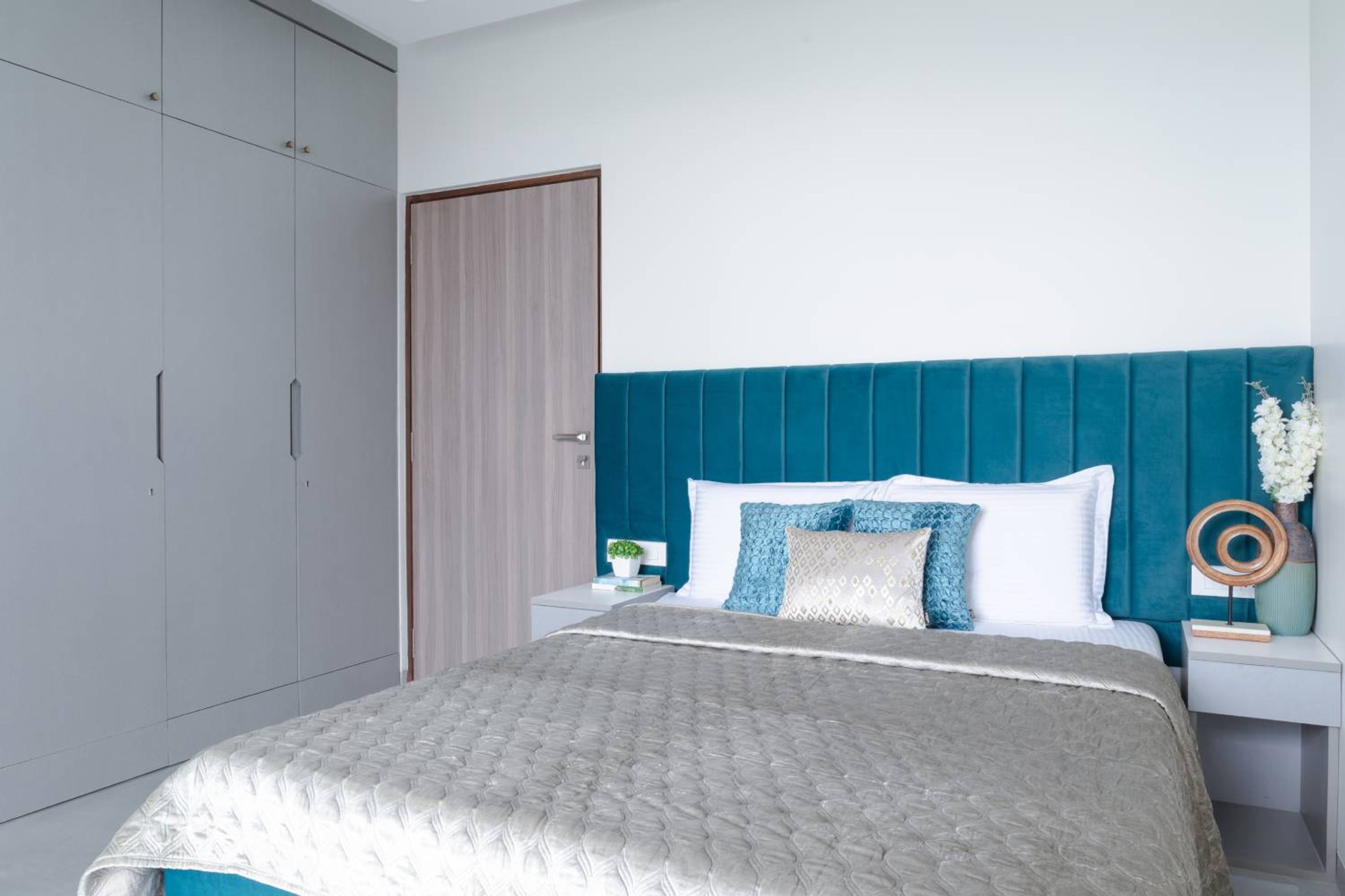 Bedroom design with blue headboard bed and 3 door grey swing wardrobe