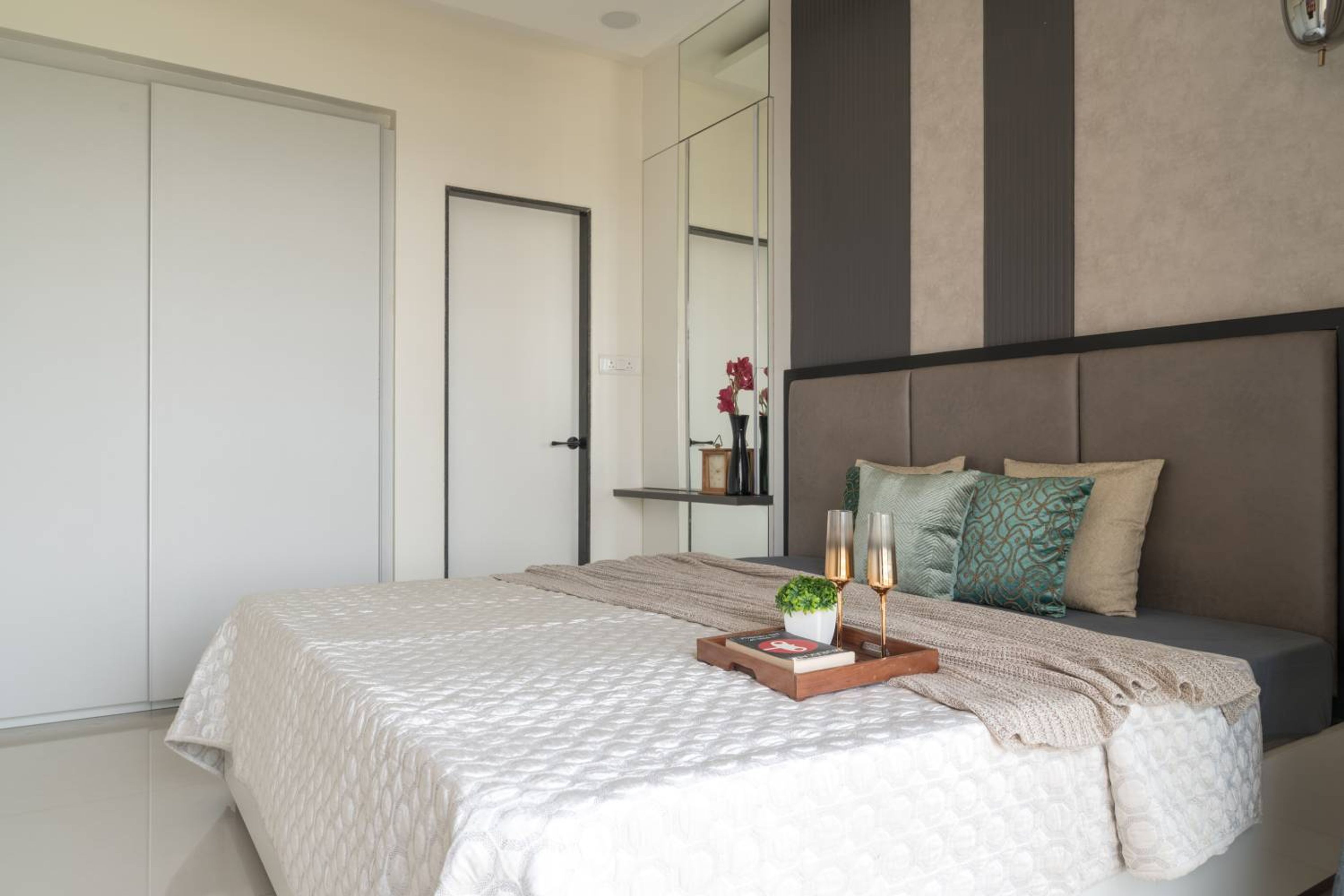 Bedroom design with grey cushioned headboard bed and 2-door white sliding wardrobe